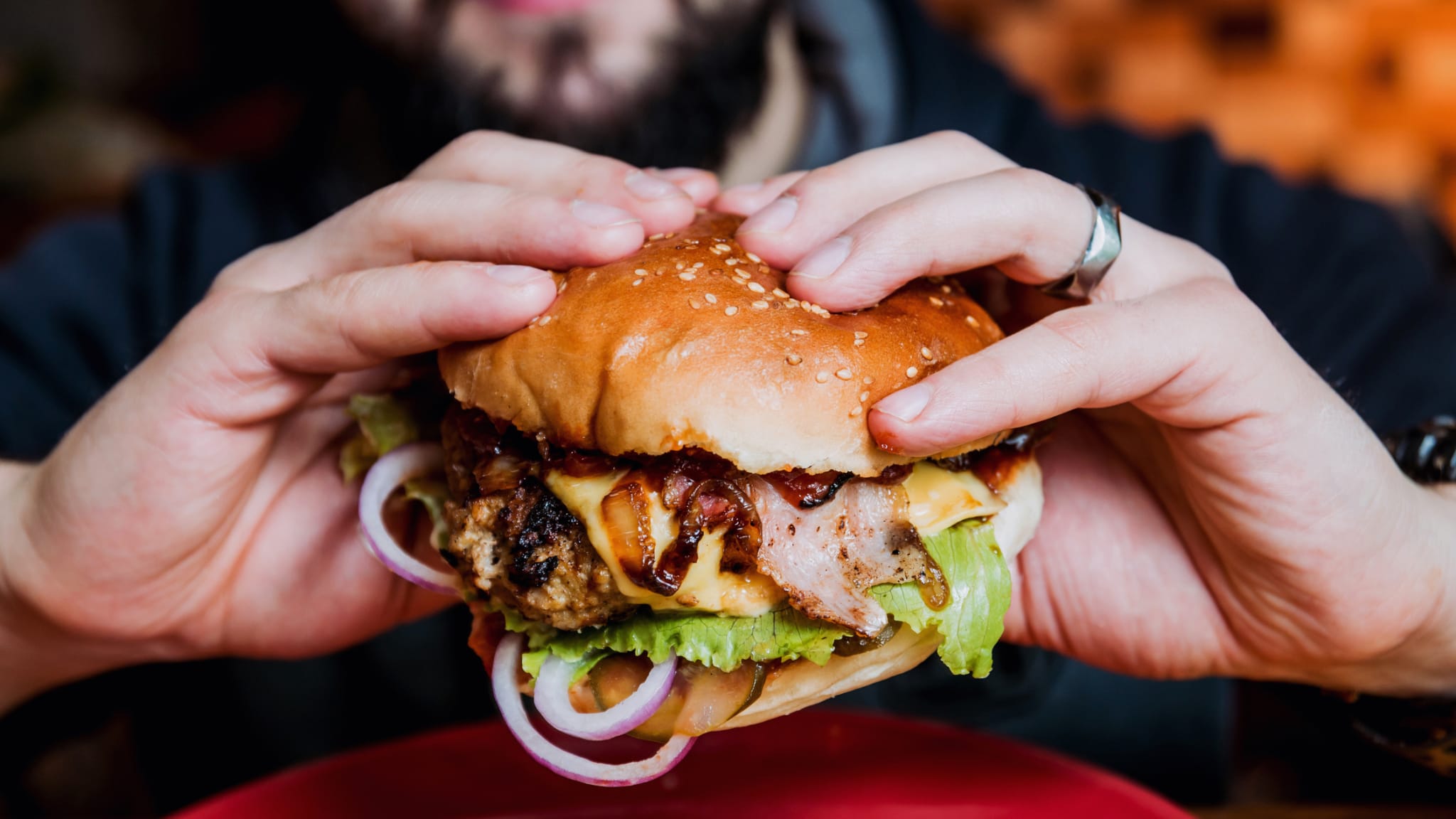 Eine Person hält einen Hamburger in den Händen.