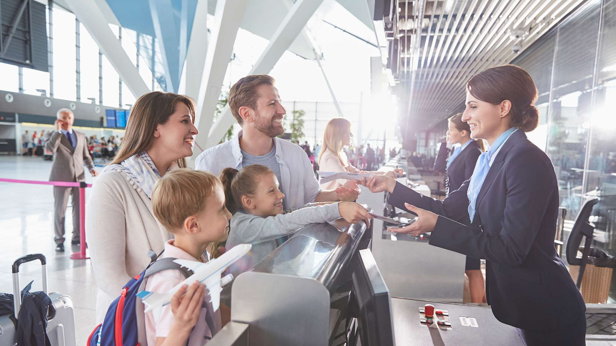 Eine Familie mit zwei Kindern checkt gemeinsam am Flughafenschalter ein.