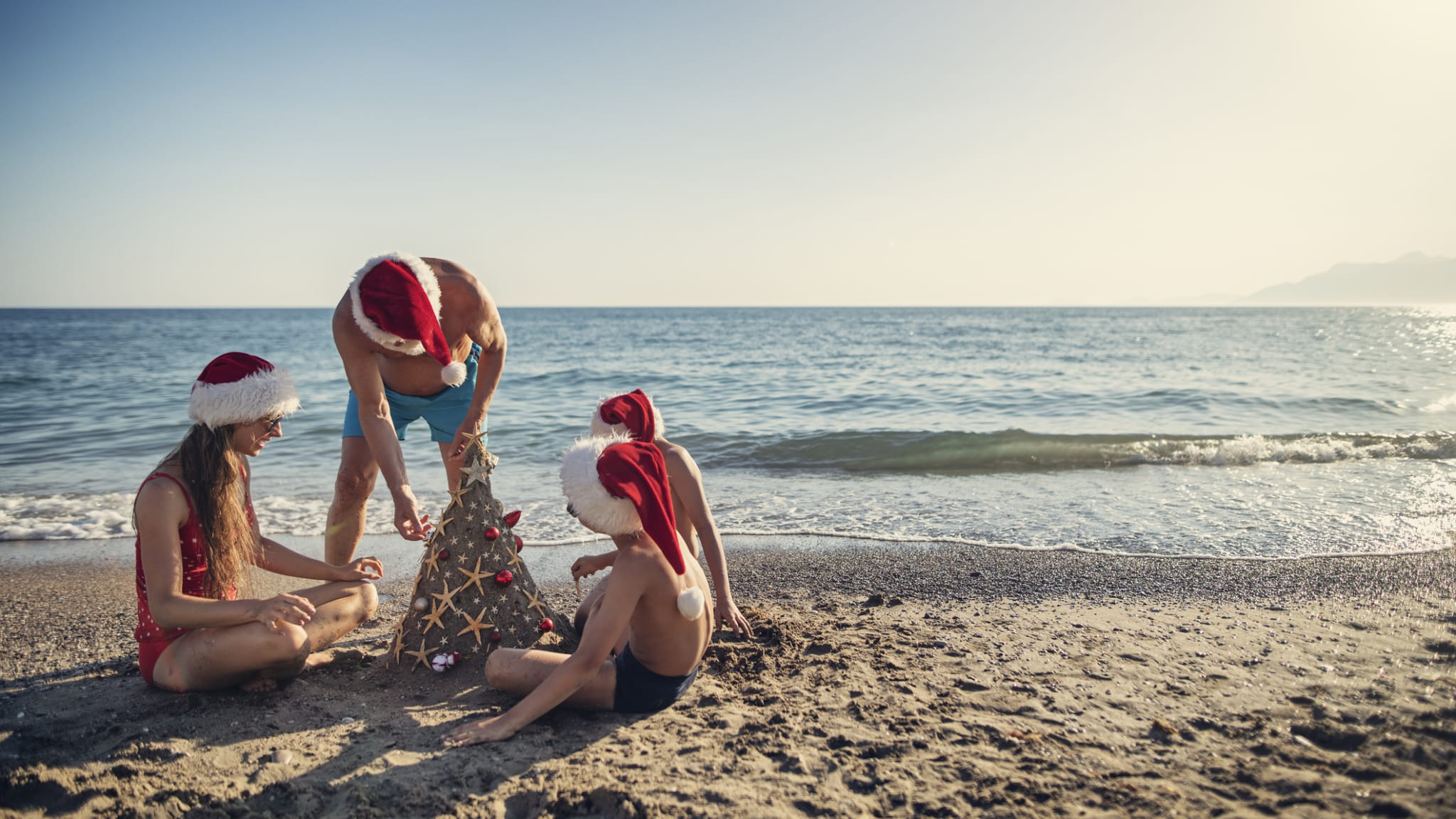 Familie schmückt einen Weihnachtsbaum am Strand