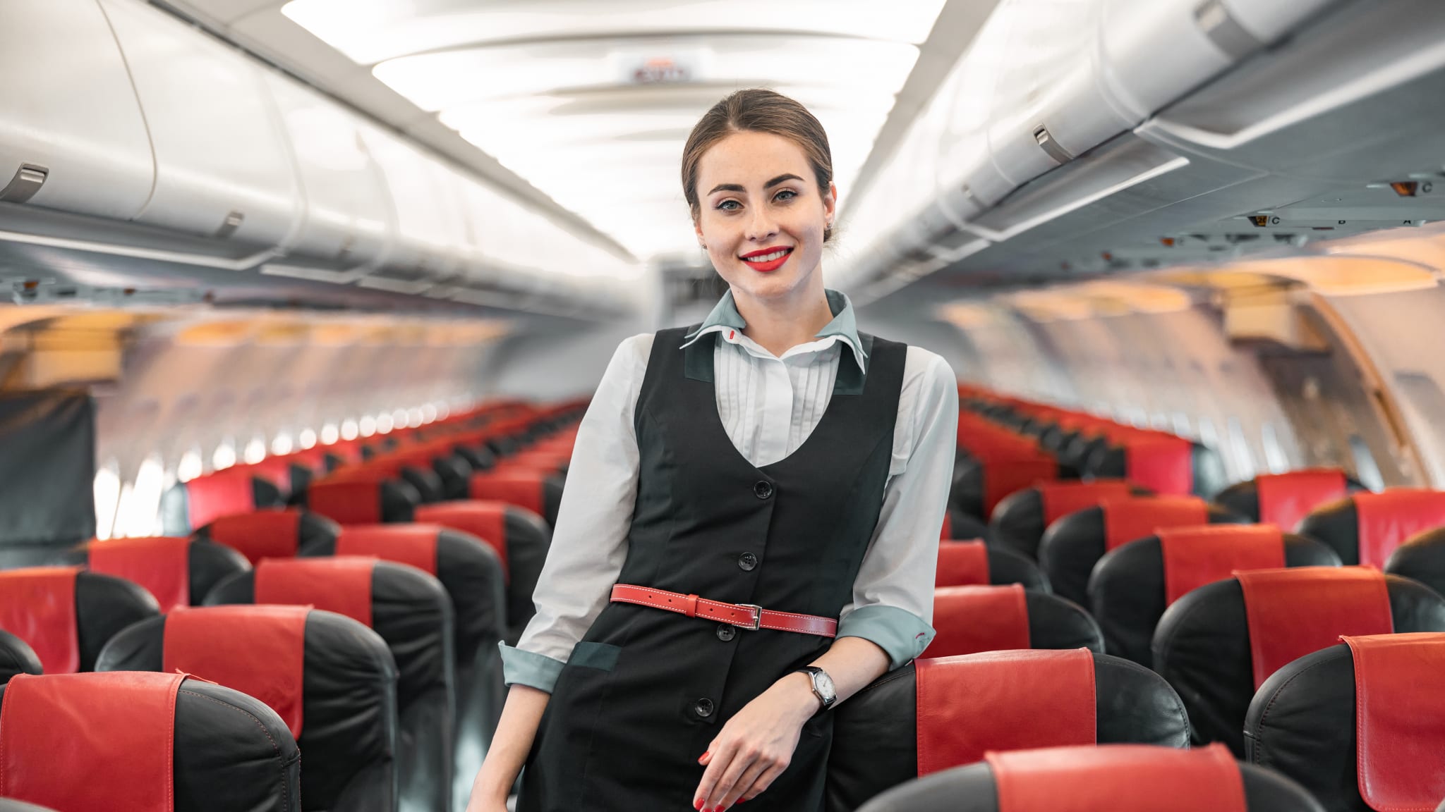 Eine FlugbegleiterIn in einer hellblauen Bluse und einem schwarzem Kleid