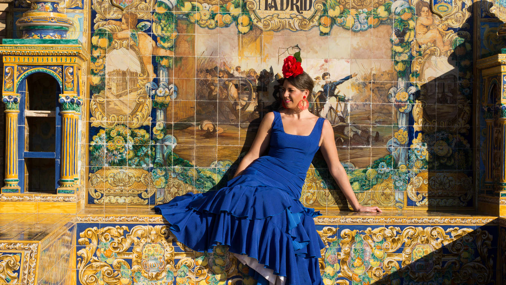 Eine Frau in einem blauen Kleid sitzt vor einem Wandgemälde mit der Aufschrift Madrid.