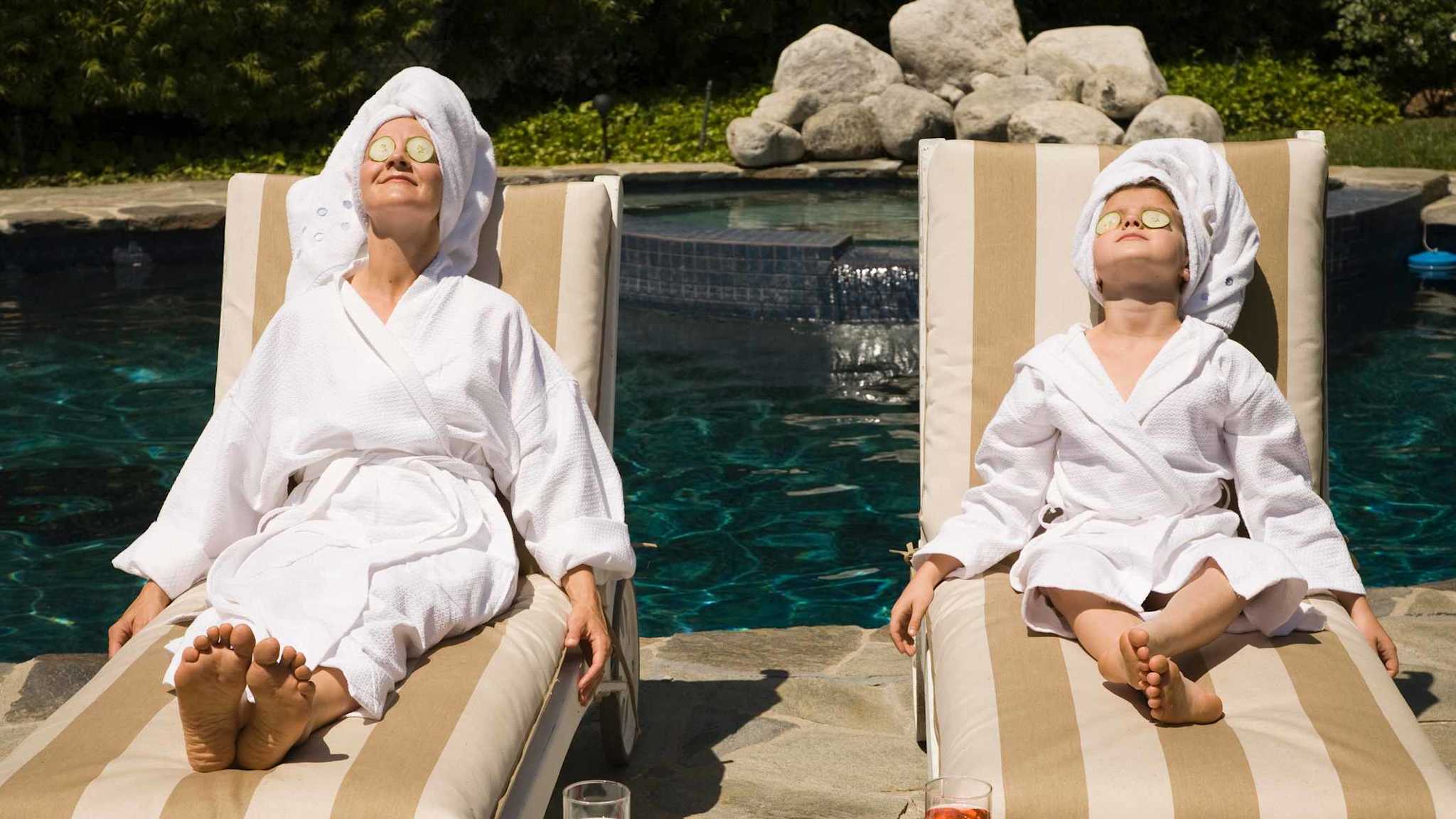 Frau und Kind entspannen mit einer Gurkenmaske im Gesicht am Pool.