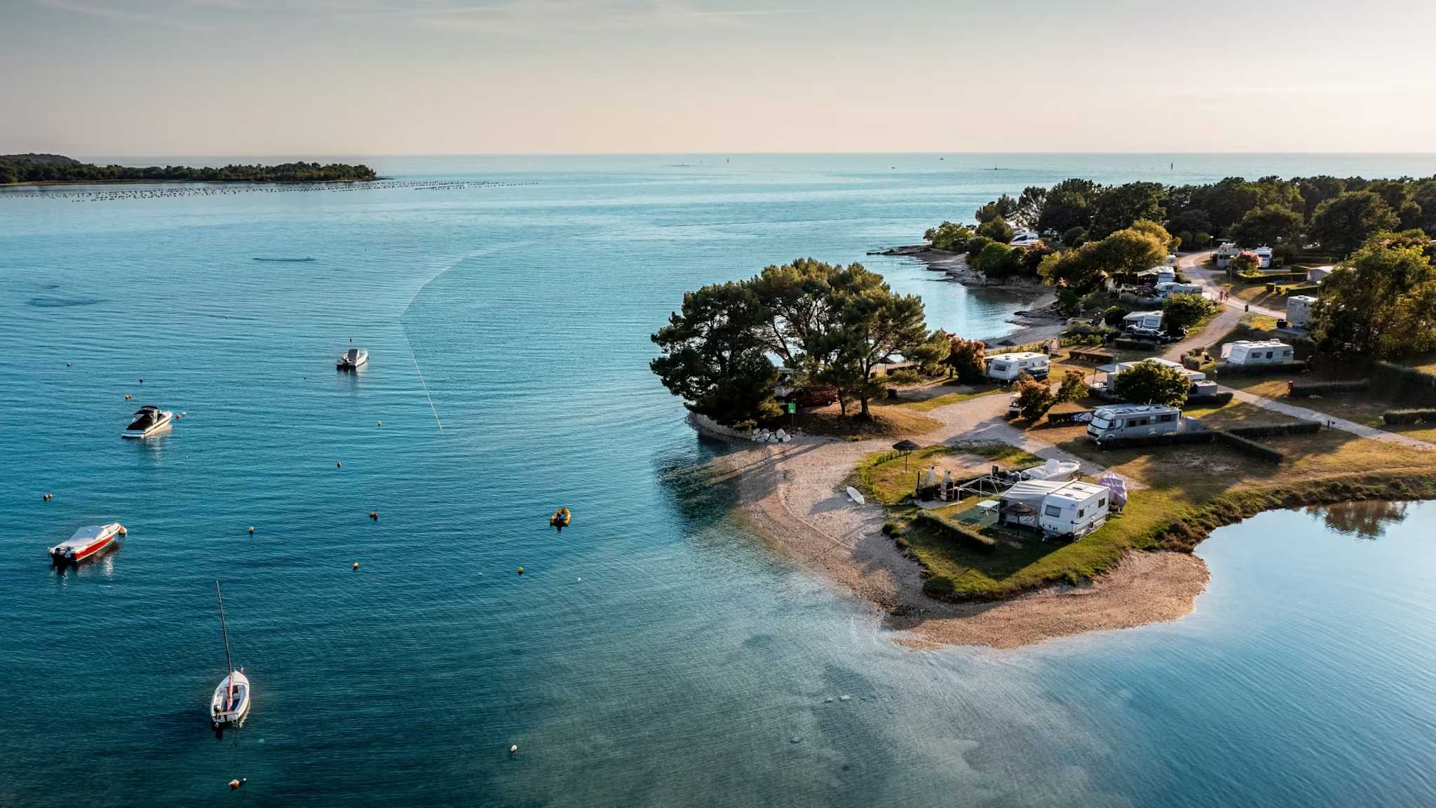 Campingwagen stehen auf einem Platz am Meer.