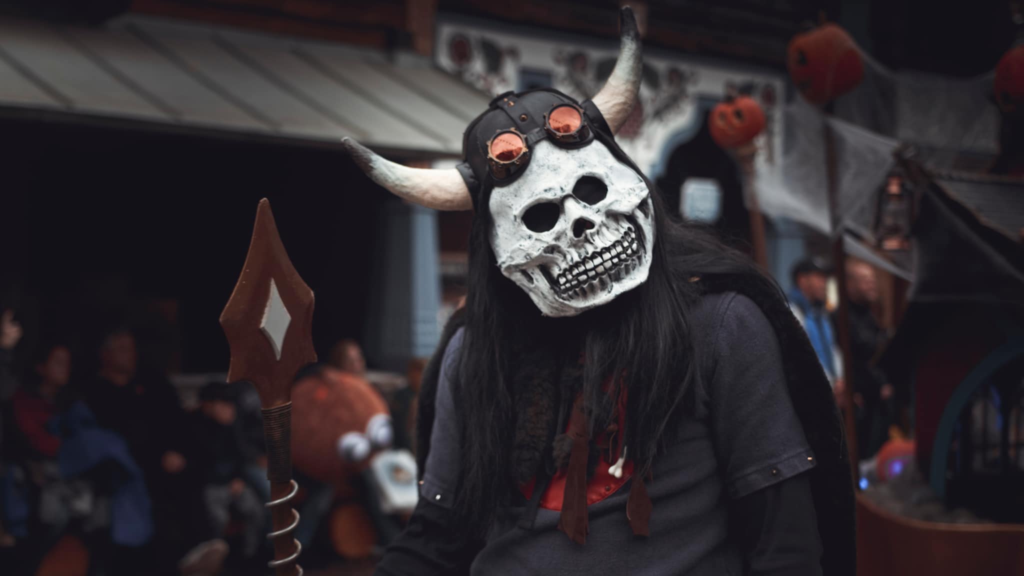 Ein mit Maske und Umhang kostümierter Mensch läuft durch einen Erlebnispark.