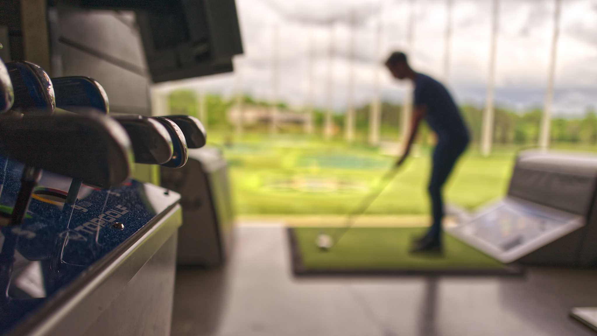 Eine Sammlung Golfschläger und ein Golfer im Hintergrund