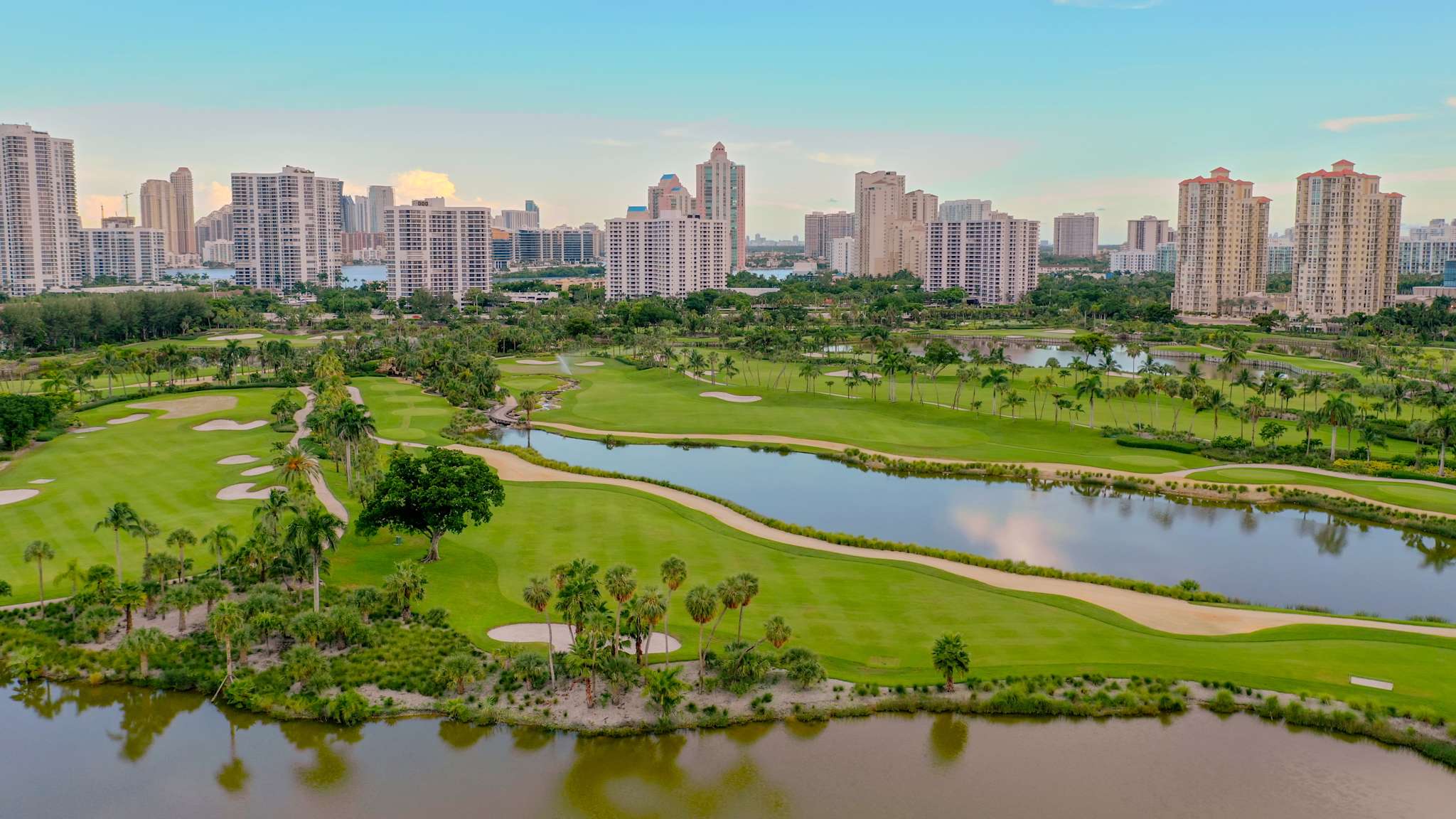 Aufnahme eines Golfkurses in Florida mit Buchten und Bepflanzung, mit Hochhäusern im Hintergrund