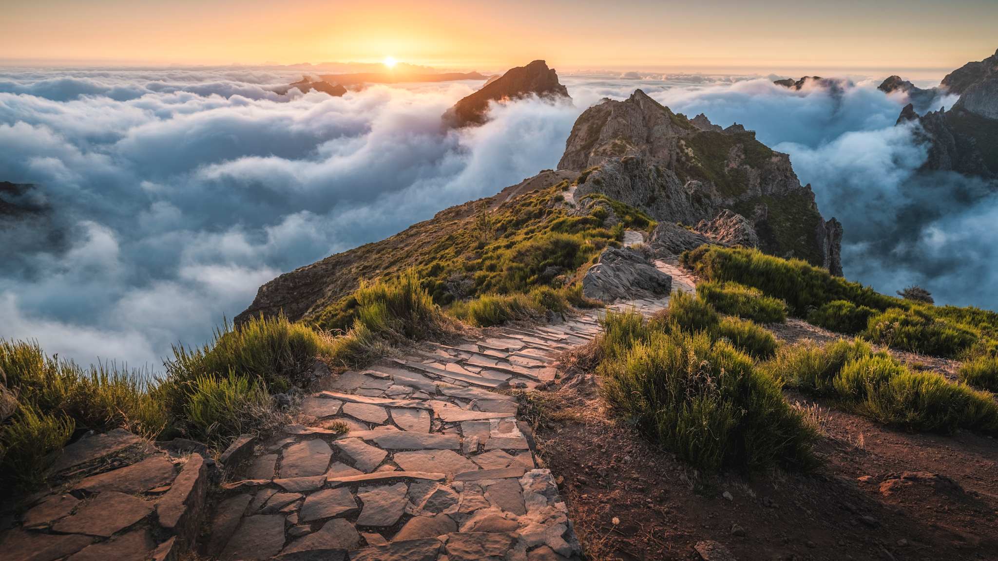 Gepflasterter Fußweg am Pico do Arieiro über den Wolken zum Sonnenaufgang, Madeira. © Marco Bottigelli via Getty Images