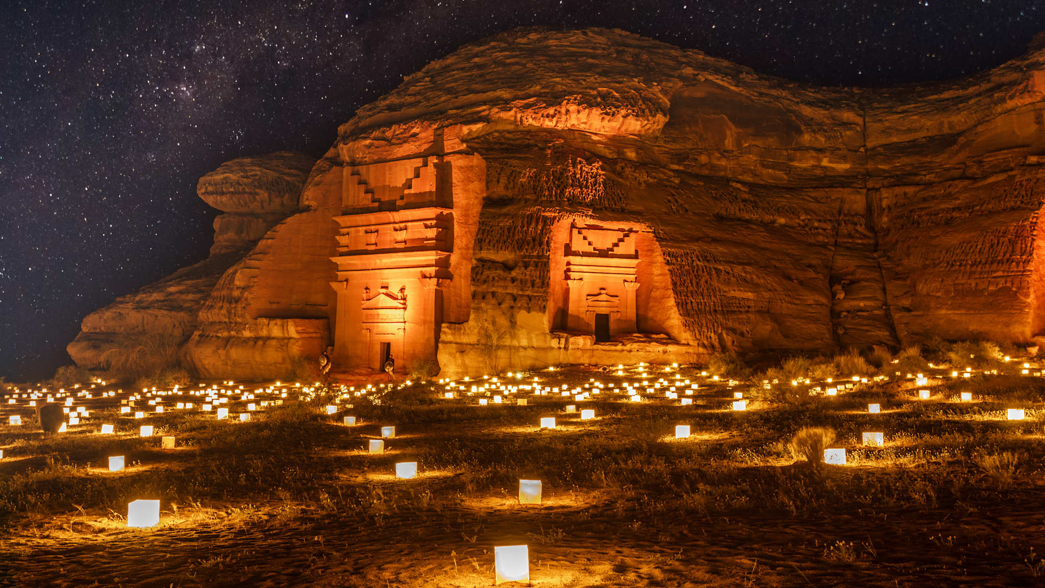 Ganz viele kleine Lampen stehen vor großen Felsengräbern.