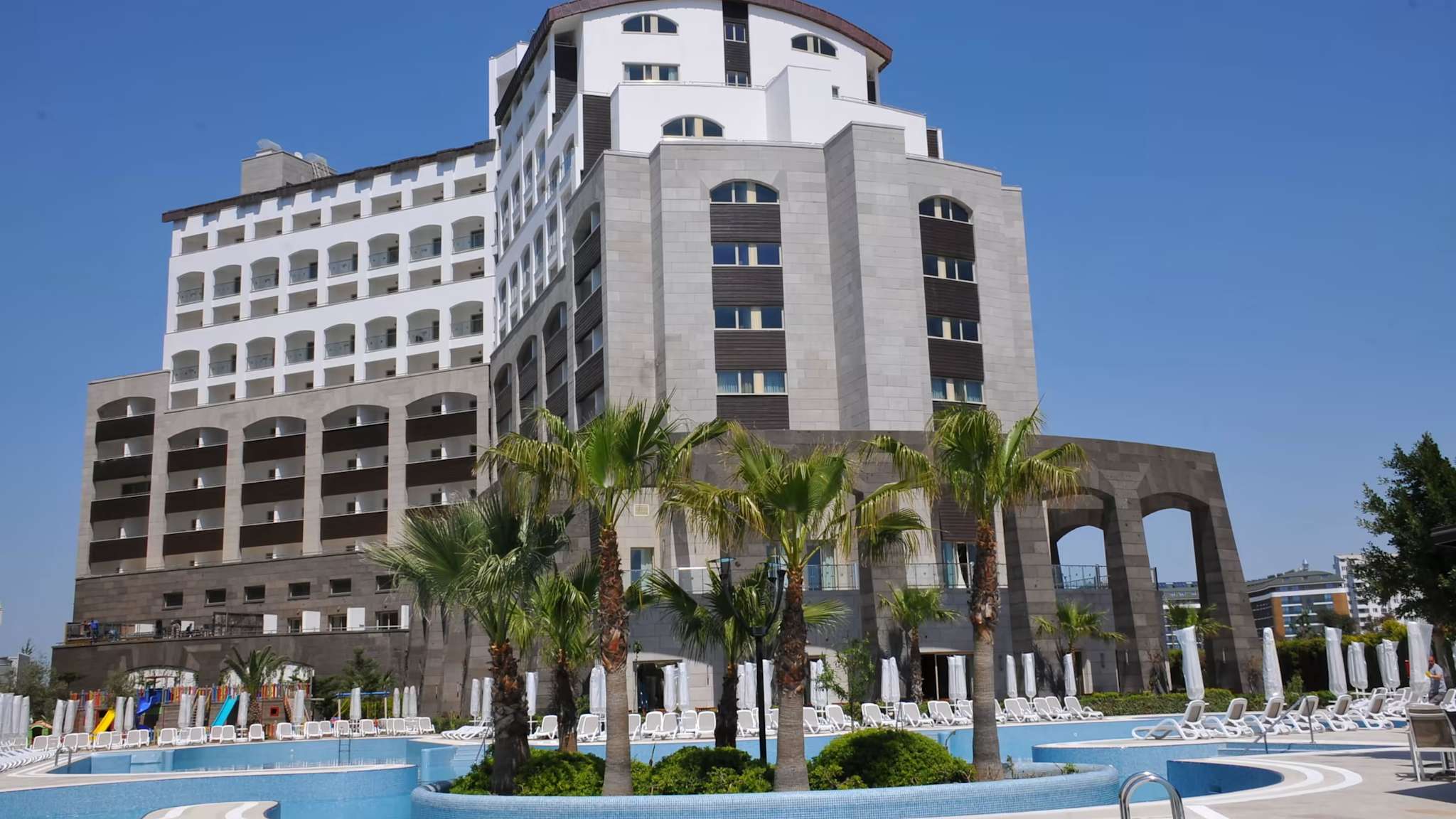 Außenanischt eines Hotels, das sich vor einem pool erhebt und mit grauem Stein verkleidet ist