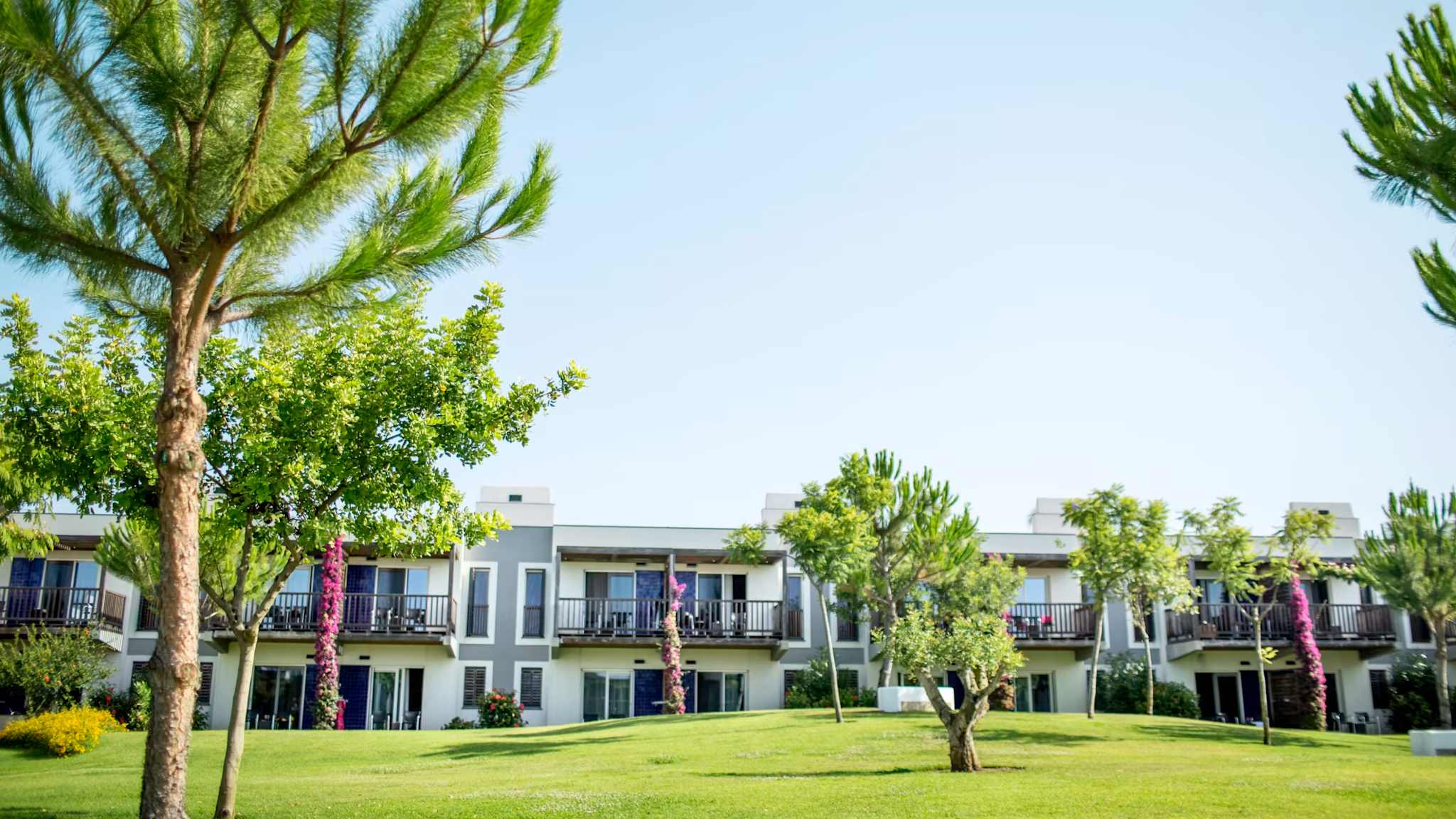 Außenansicht einer Hotelanlage mit Wiese vor einem zweistöckigen Gebäude