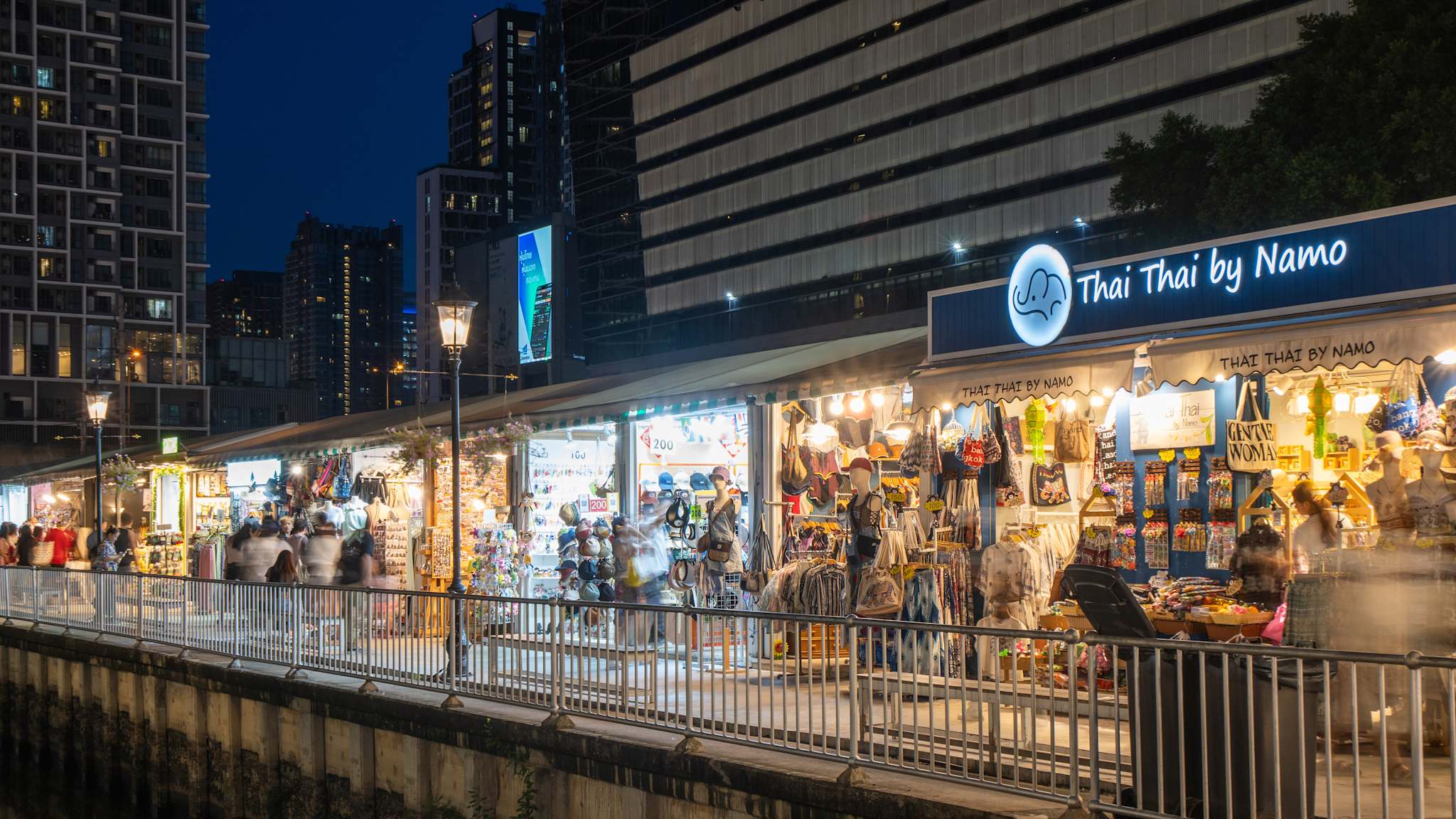 Eine Straße in Bangkok, bei Nacht die voller kleiner Läden und Stände ist.