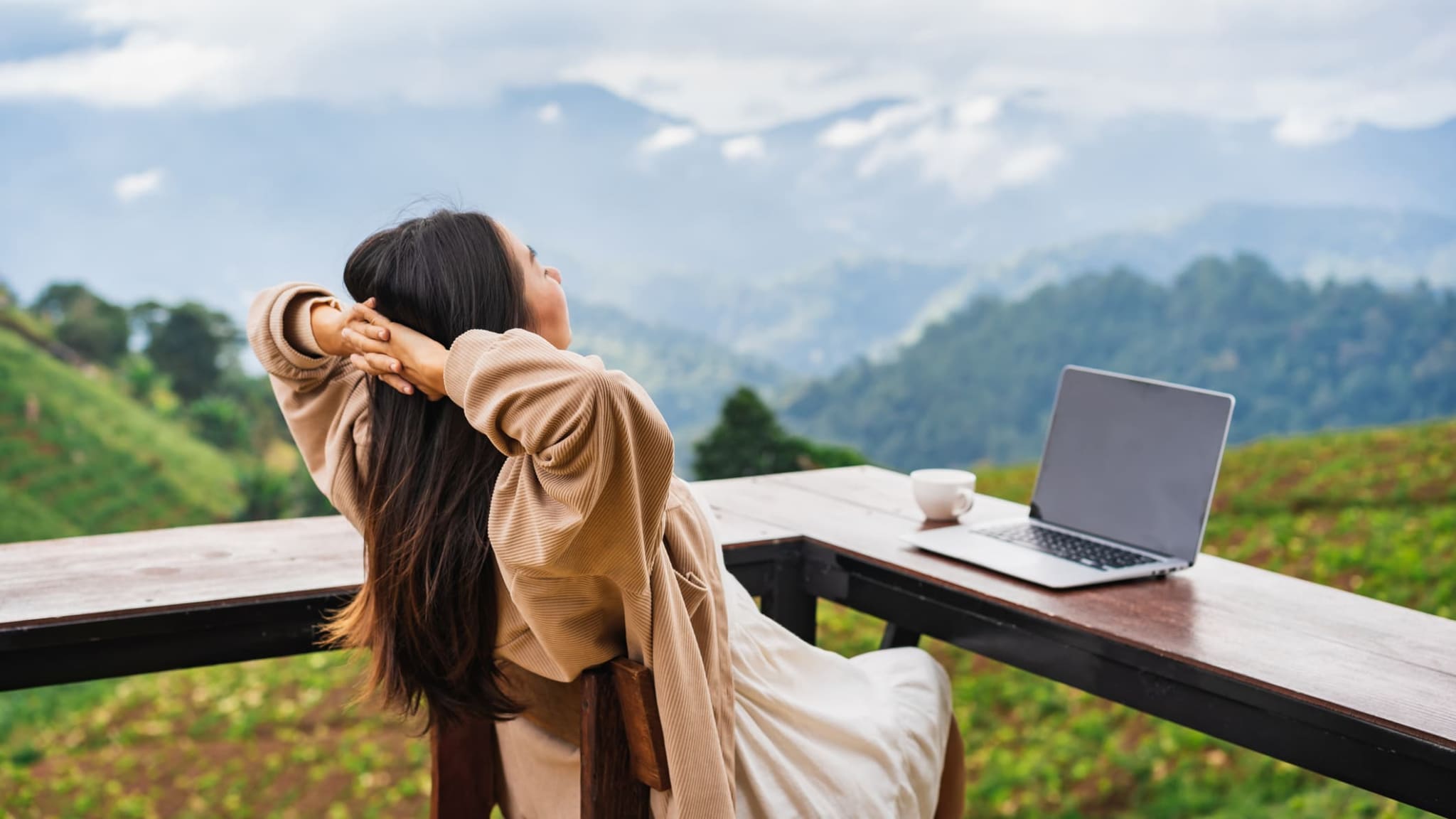 Junge Frau arbeitet online und genießt die Aussicht auf die Berge.