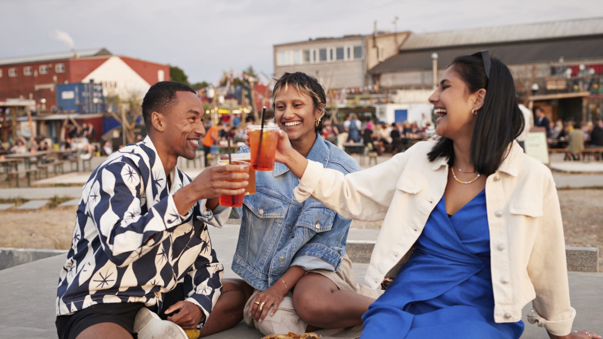 Junge Menschen stoßen mit einem Cocktail an.