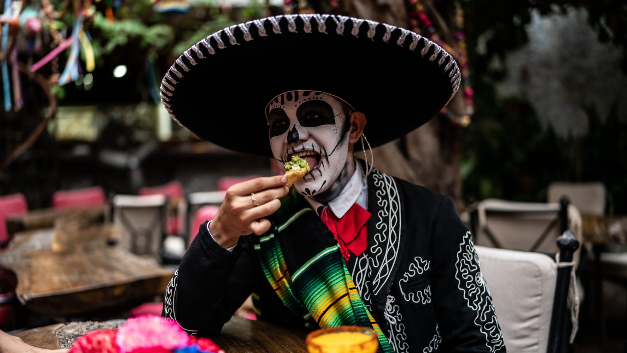 Junger Mann isst und feiert den Tag der Toten in der Bar.