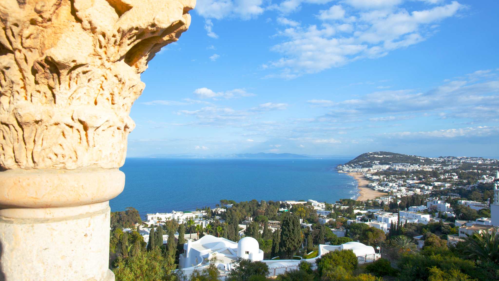 Blick an einer Säule vorbei auf eine Stadt am Meer