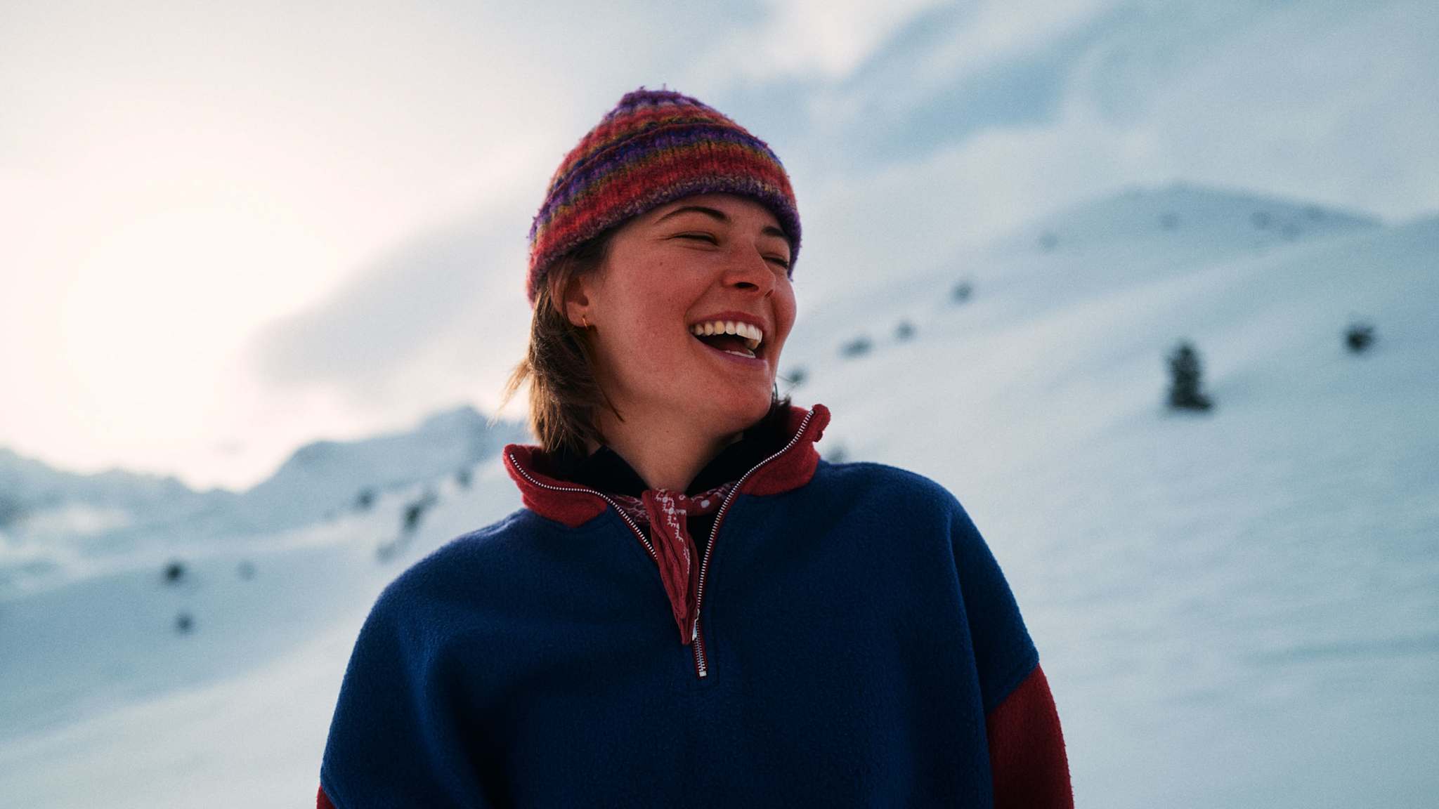 Halbportrait einer lachenden Frau im Schnee.