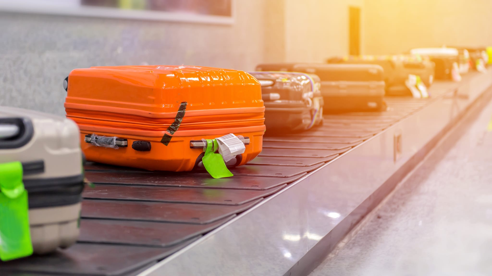 Ein orangener Koffer auf dem Kofferband