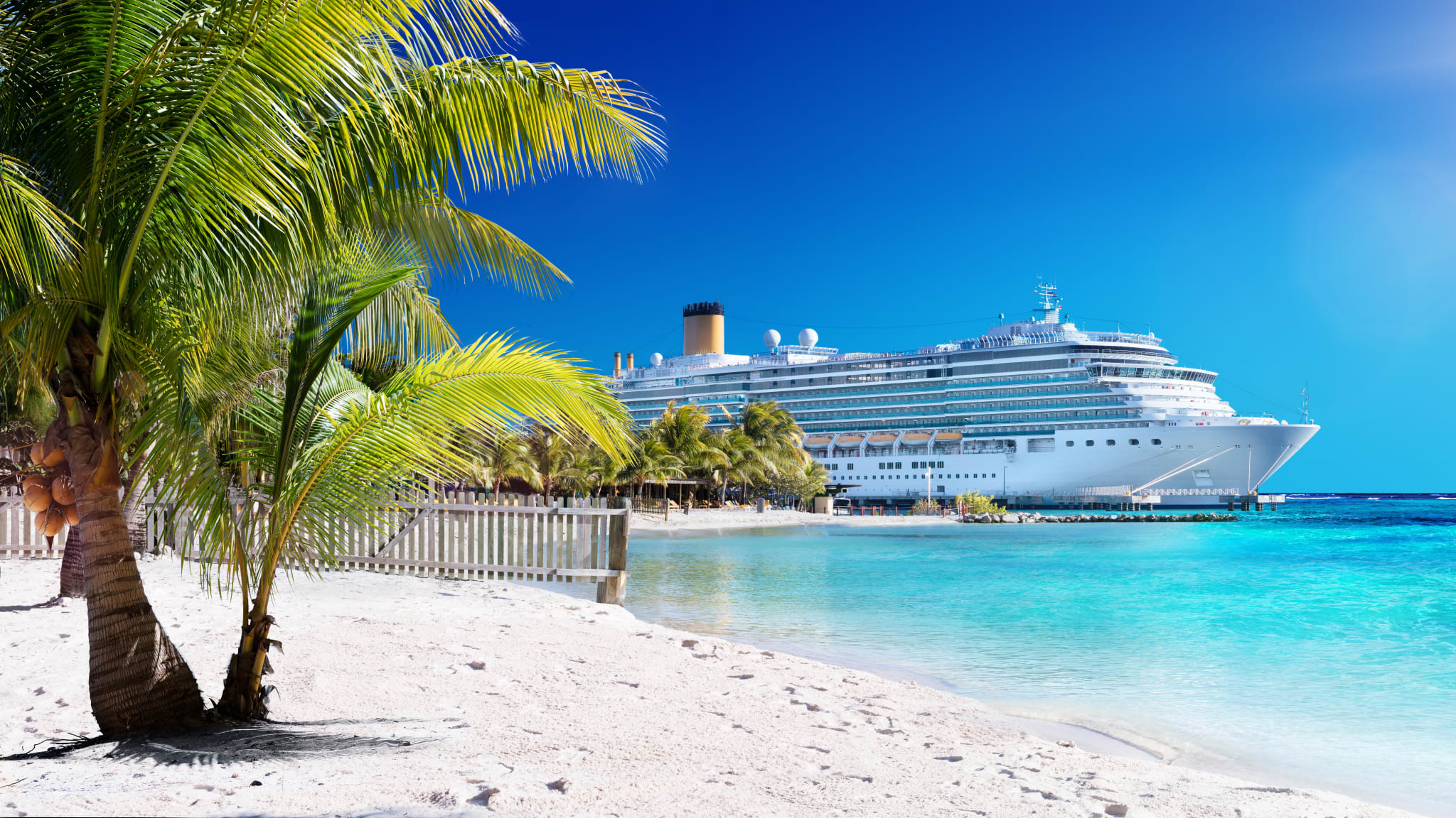 Kreuzfahrtschiff an einem Srand mit türkisem Wasser