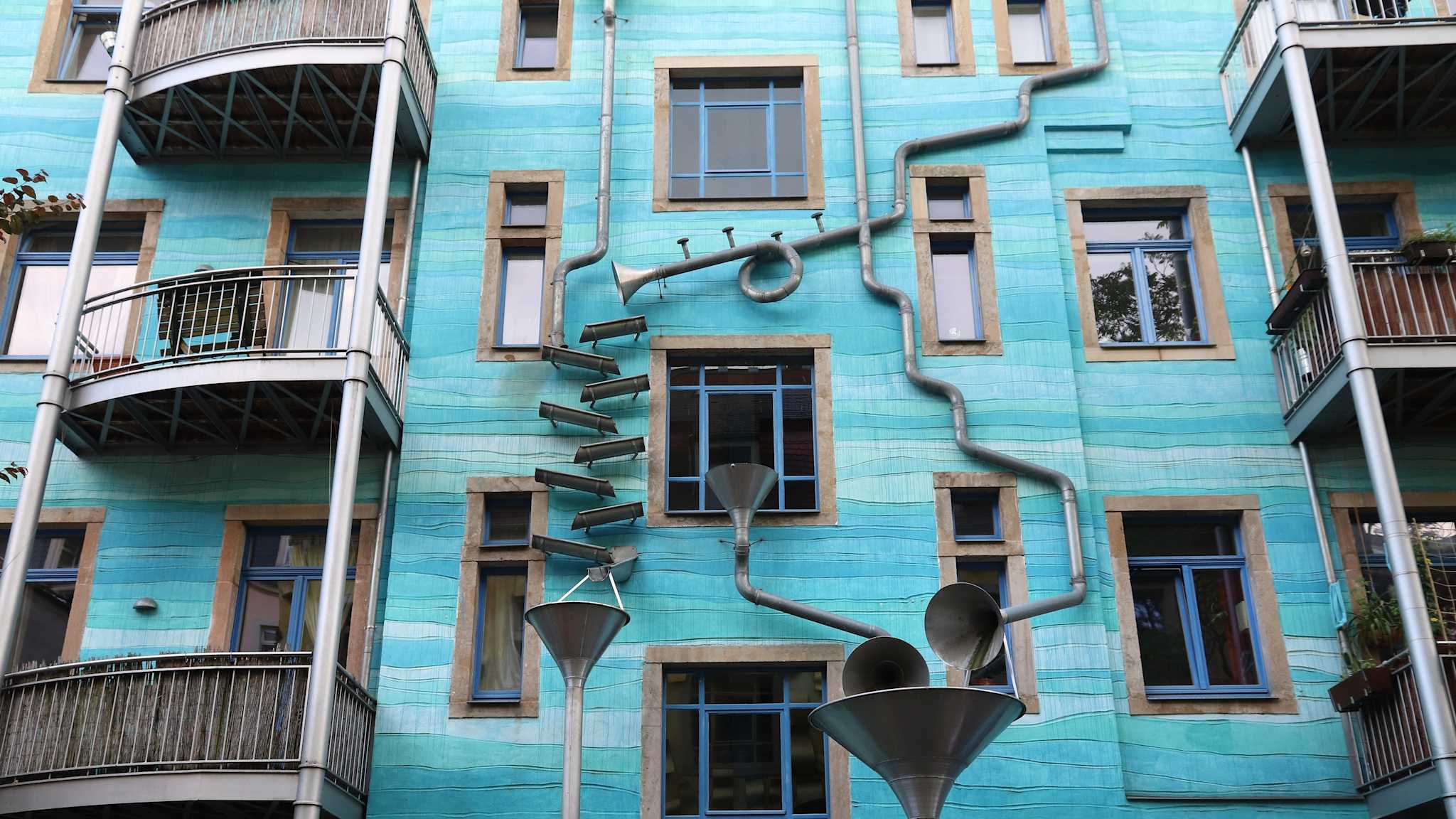 Eine Hauswand mit einer Kunstinstallation aus Regenrohren.