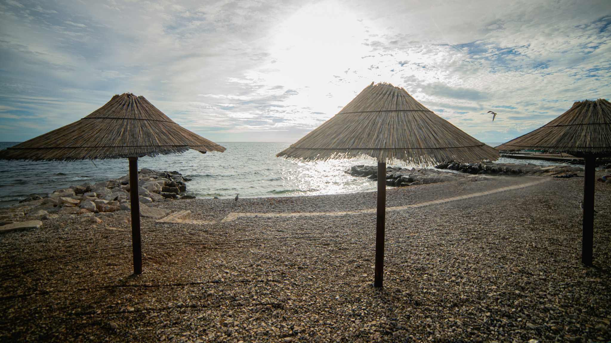 Drei Sonnenschirme stehen an einem Strand.