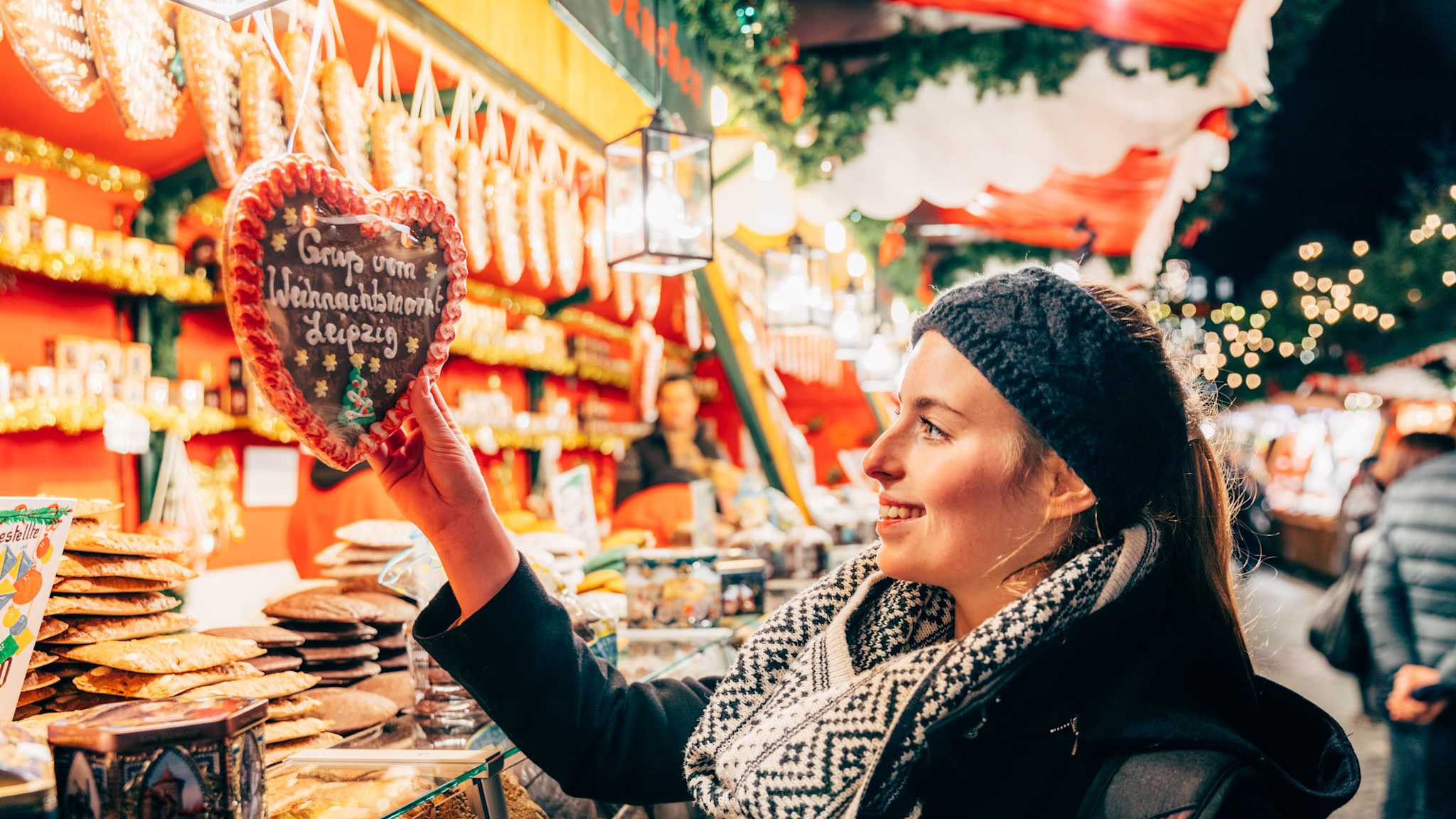 Eine Frau lächelt ein Lebkuchenherz an.