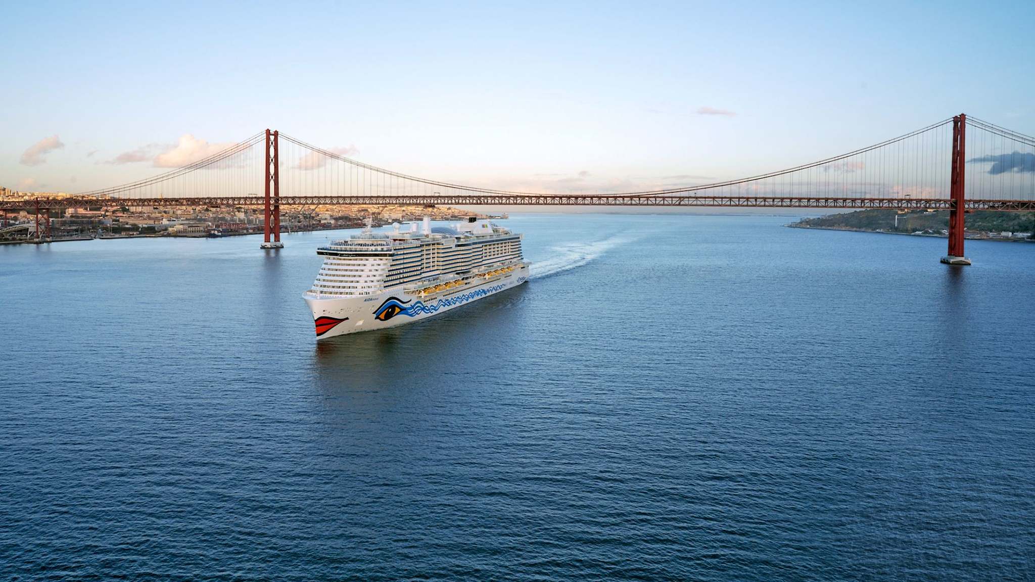 Ein Kreuzfahrtschiff fährt unter einer Brücke hindurch.