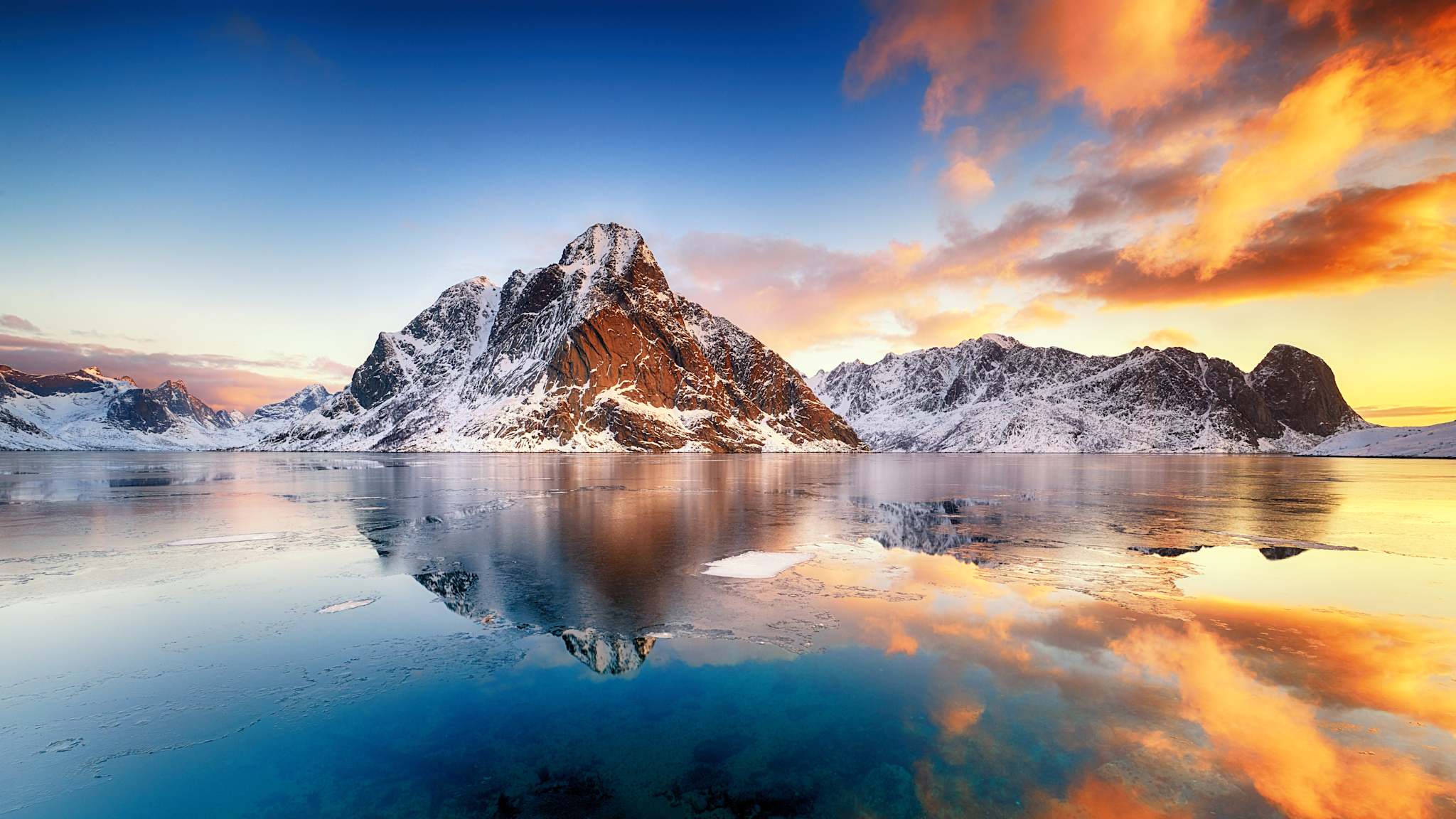 Schneebedeckte Berge spiegeln sich im Eiswasser.