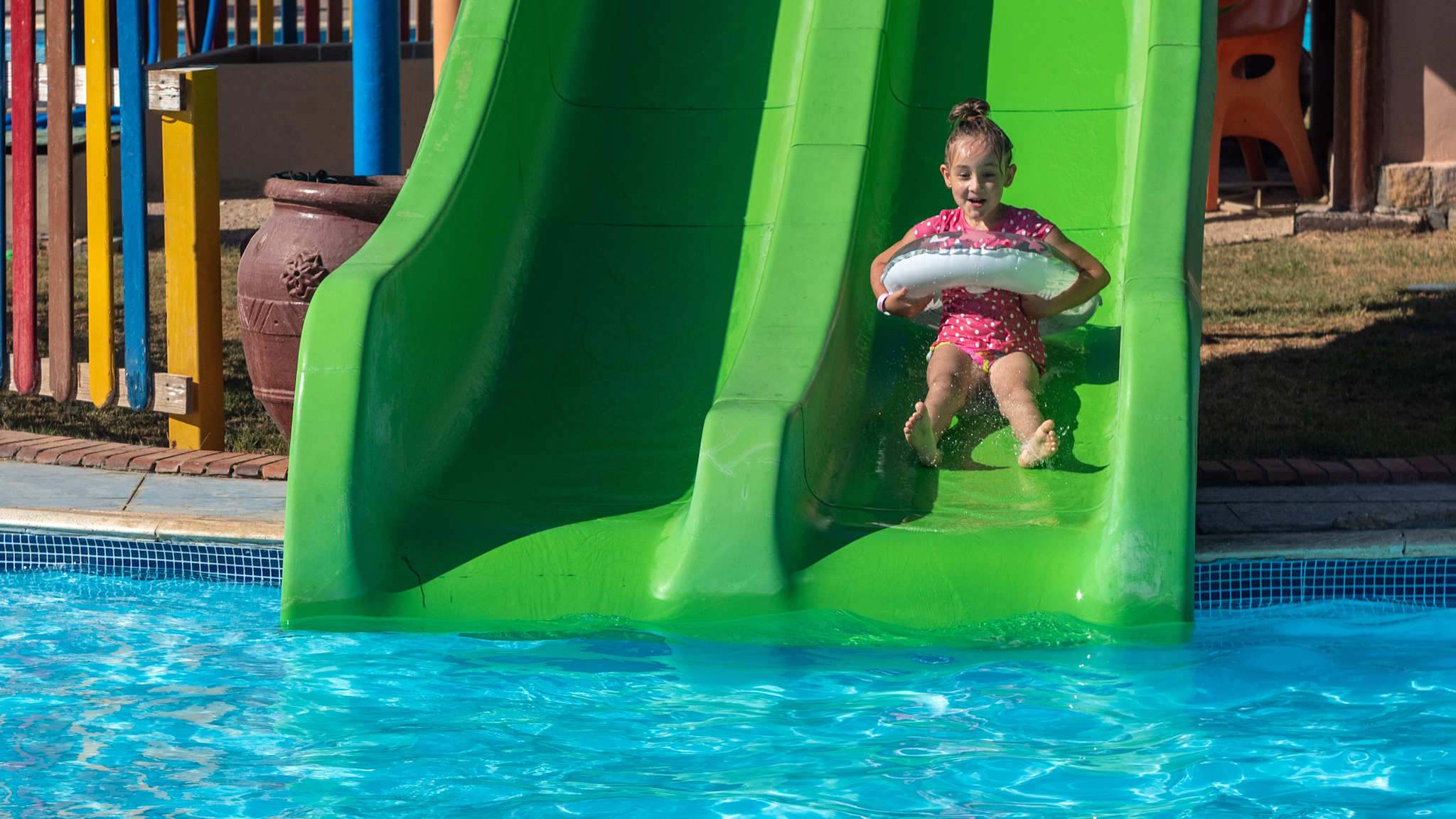 Ein Mädchen rutscht mit einem Schwimmring auf einer Rutsche.