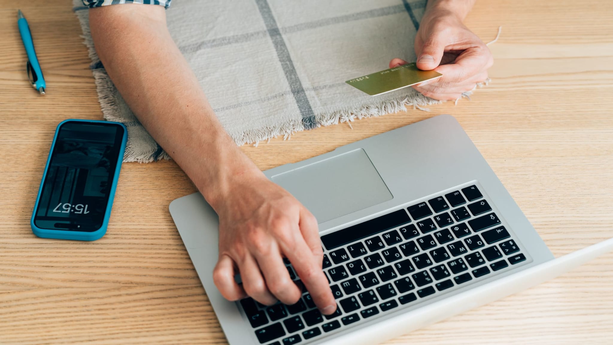 Ein Mann gibt seine Kreditkartendaten am Laptop ein.