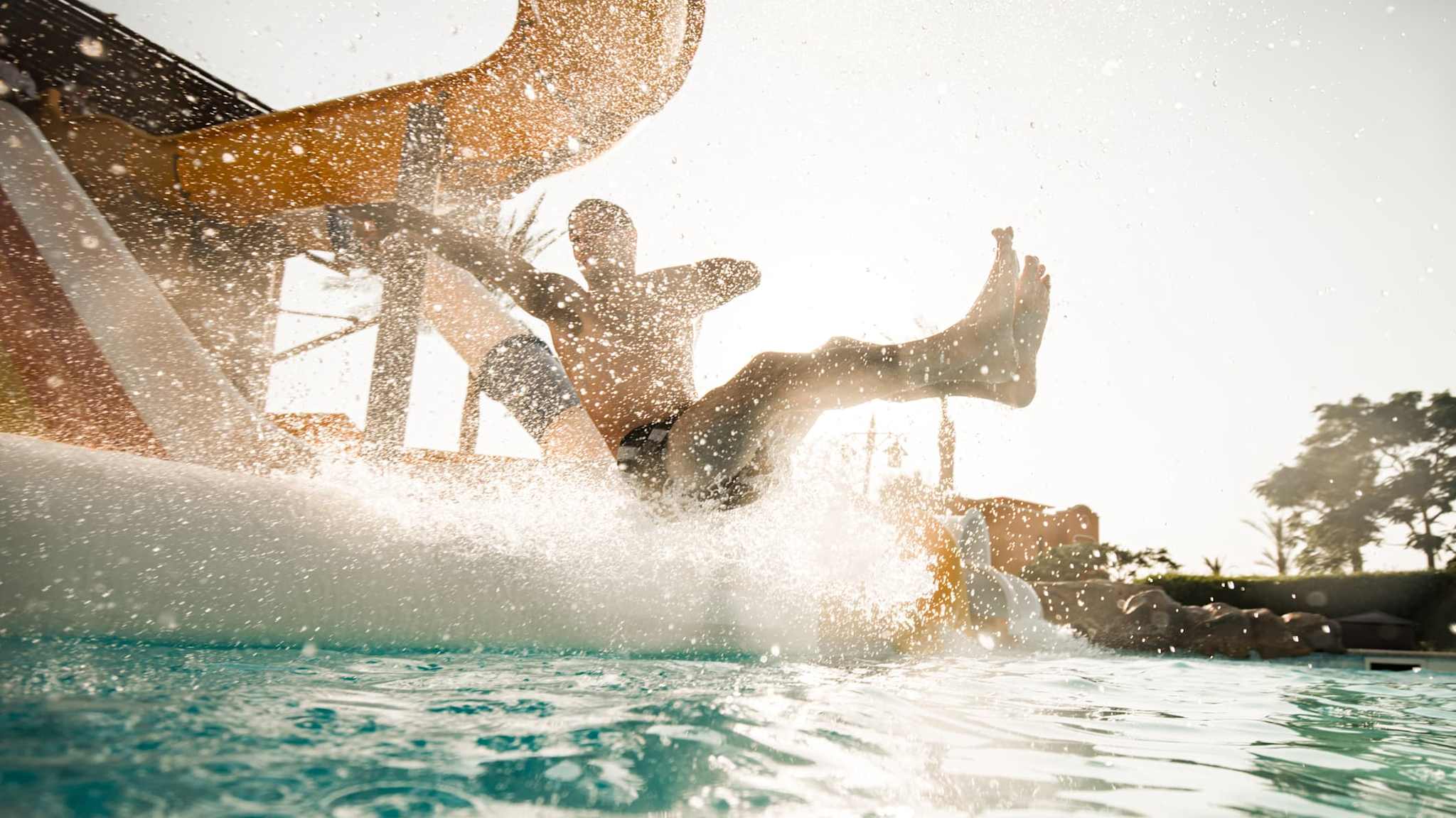 Ein Mann rutscht in den Pool.