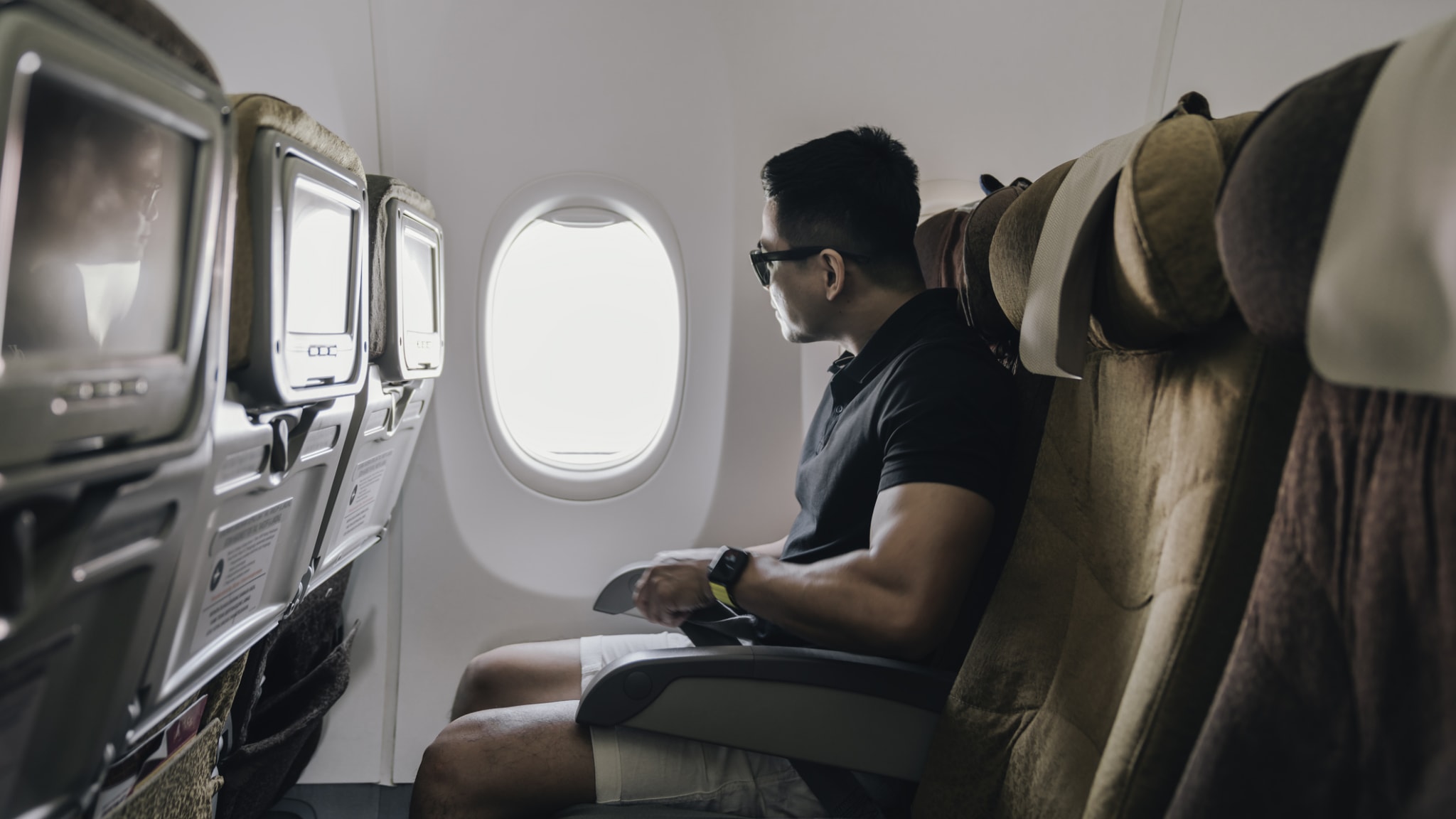 Mann schaut in einem Flugzeug aus dem Fenster. © rudi_suardi/E+ via Getty Images