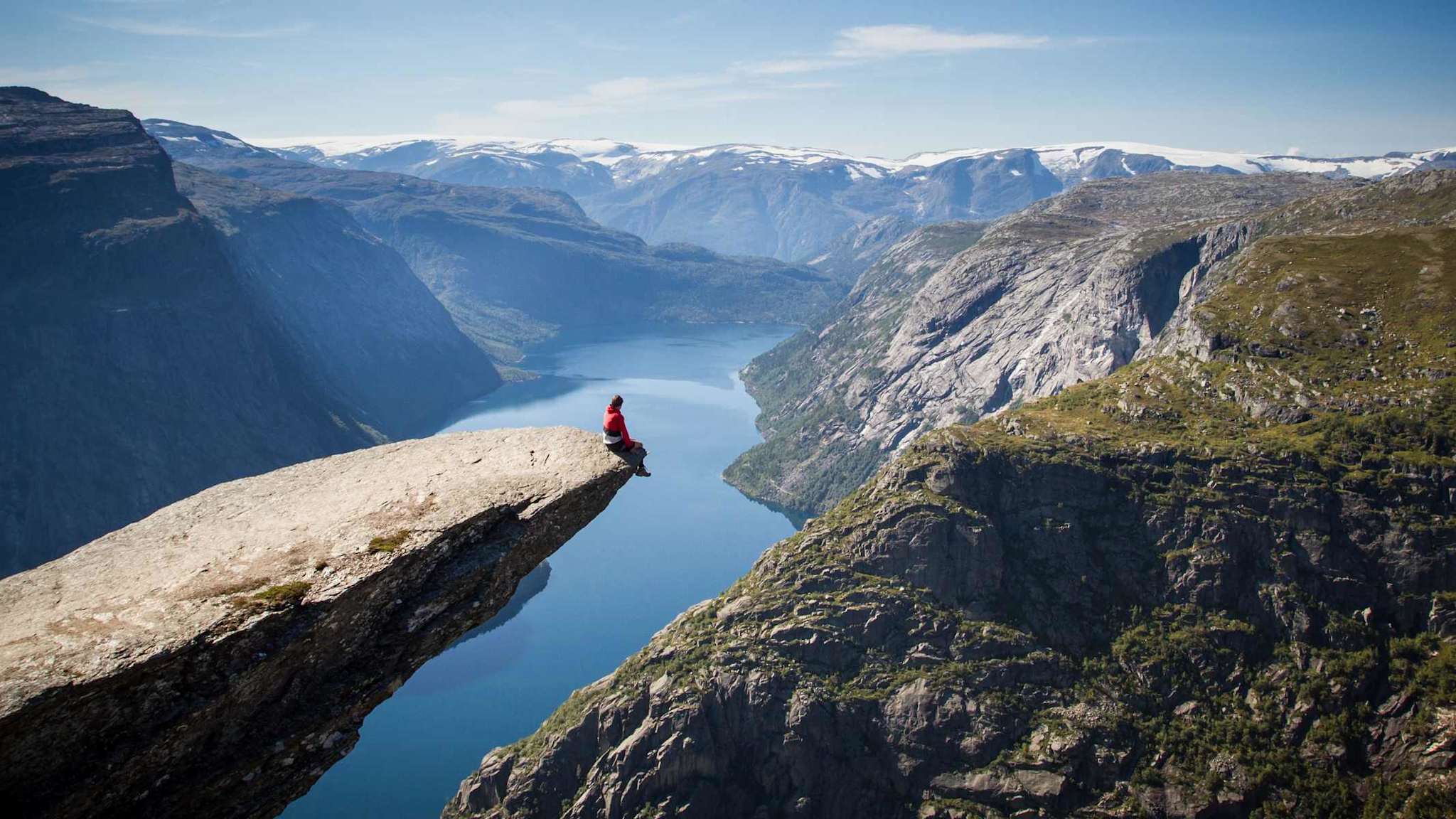 Mann sitzt auf Trolltunga in Norwegen.