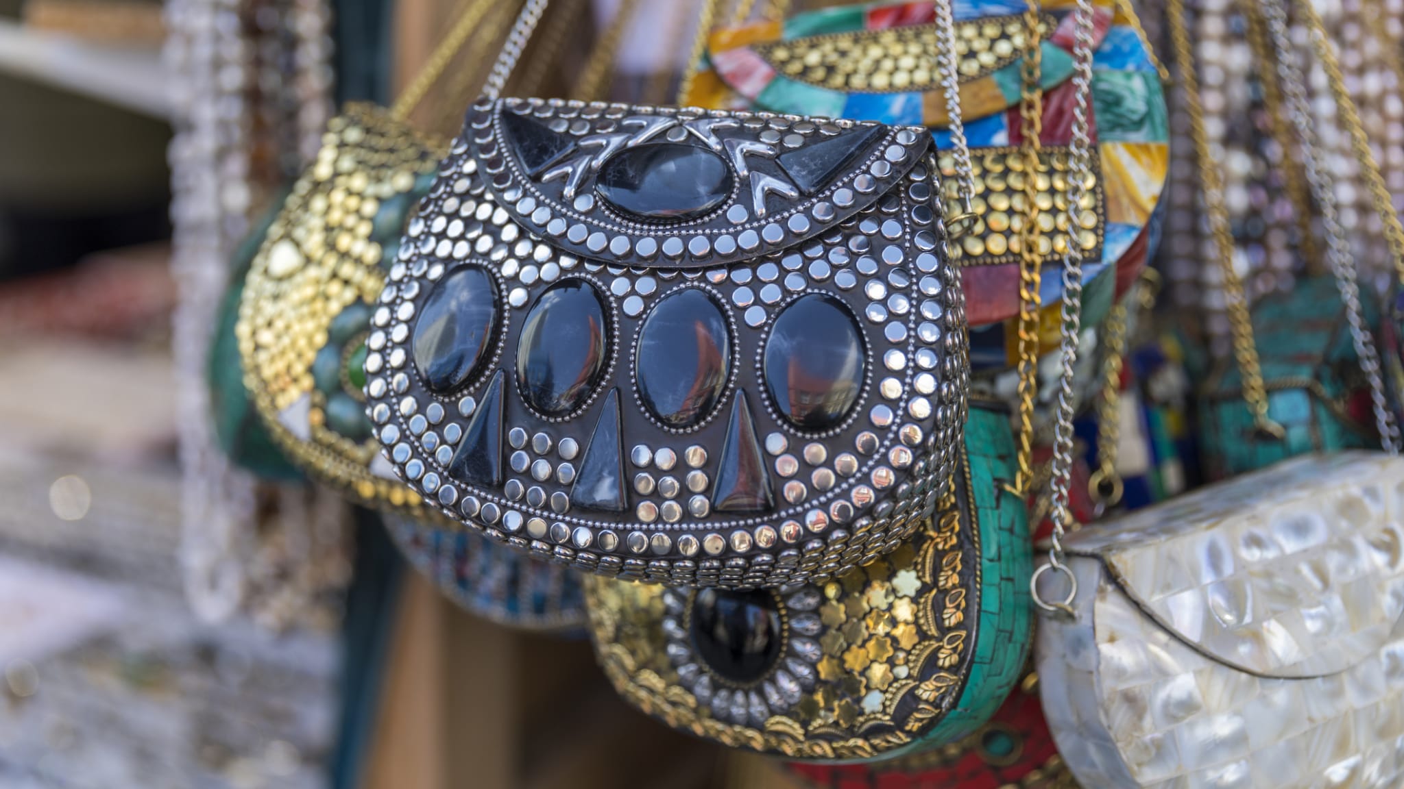 Mehrere verzierte Handtaschen hängen an einem Marktstand.