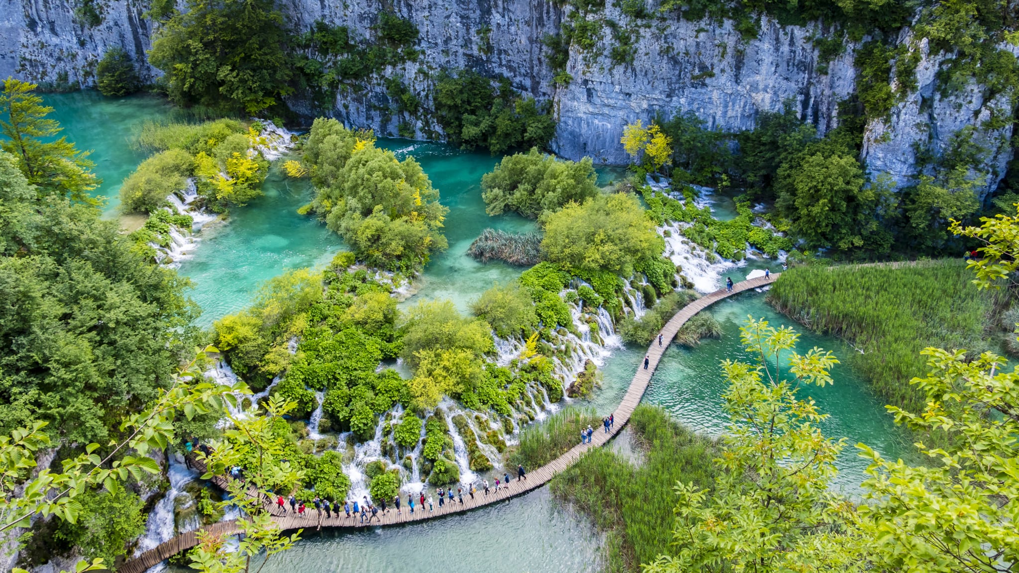Menschen überqueren eine Brücke im Plitvicer Seen Nationalpark in Kroatien.