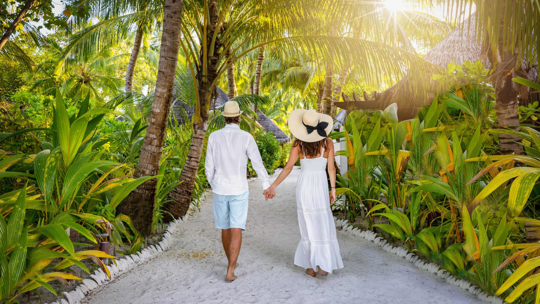 Ein Pärchen läuft durch einen Palmengarten Hand in Hand.