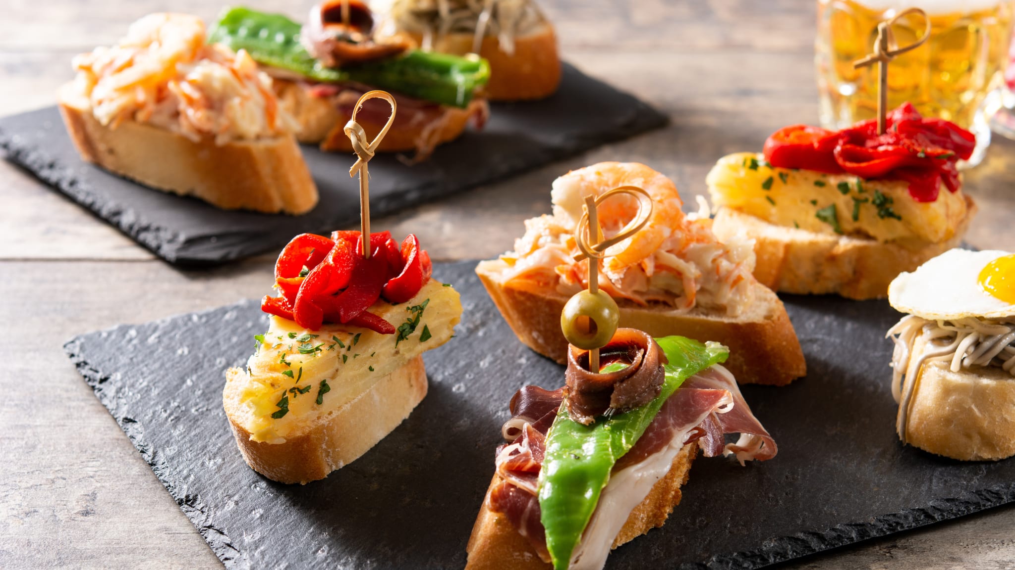 Man sieht eine Schieferplatte mit 8 Häppchen, die von Holzspießchen zusammengehalten werden