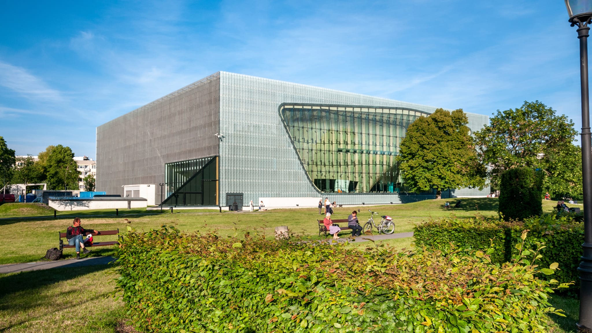 Menschen rasten auf Bänken vor einem Museumsgebäude