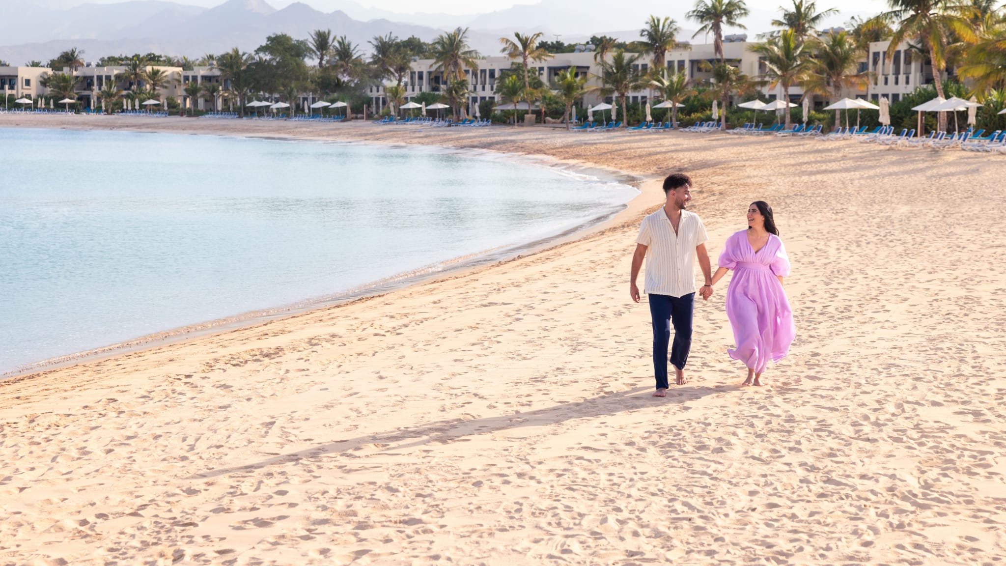 Ein Paar läuft Hand in Hand über einen Strand in Ras Al Khaimah