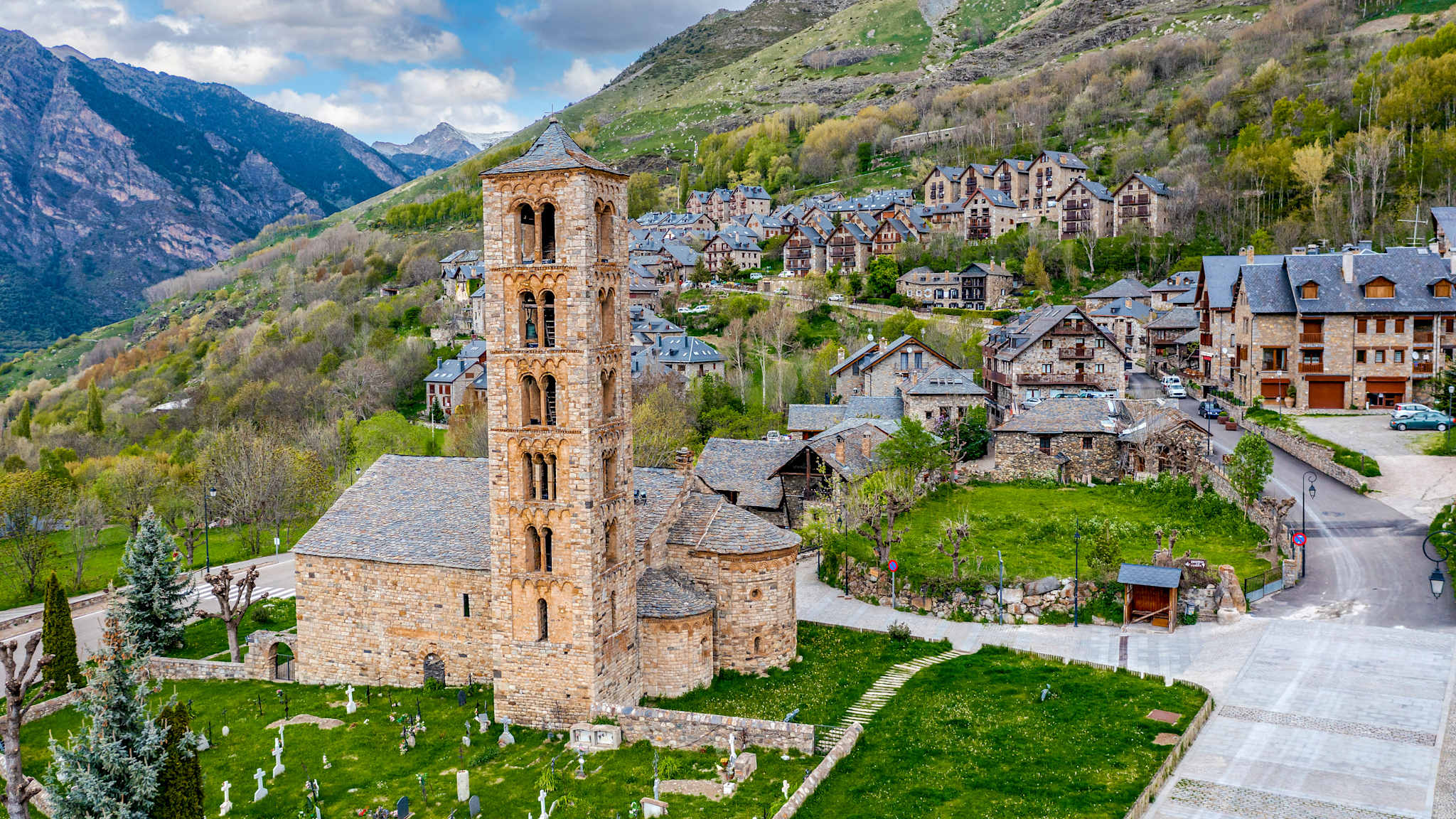 In einem Bergdorf voller Steinhäuser steht eine alte romanische Kirche mit einem hohen Kirchturm