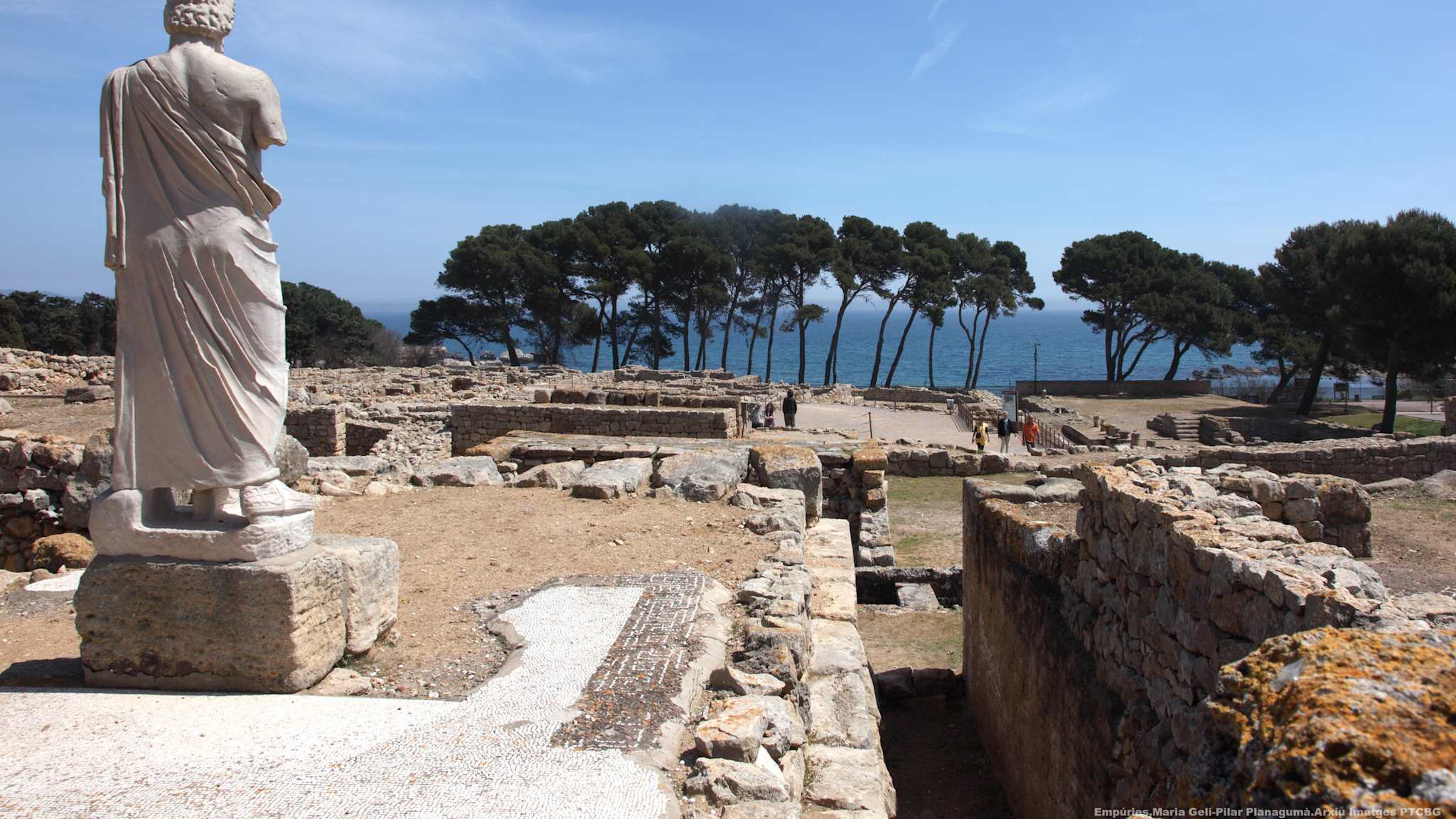 Eine Statue blickt über ein antikes Ruinenfeld.