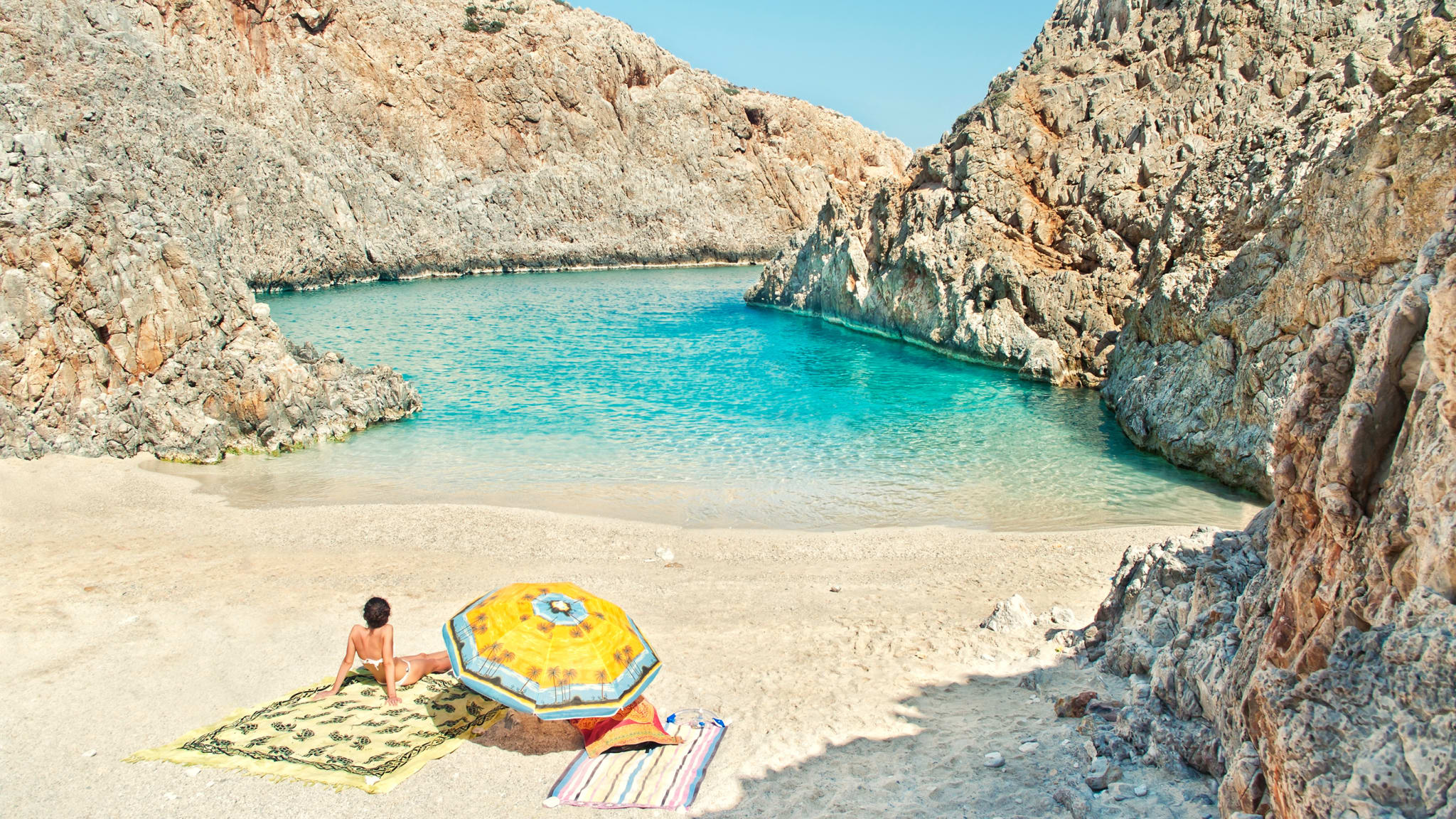 Eine Frau sitzt an einem leerem Strand