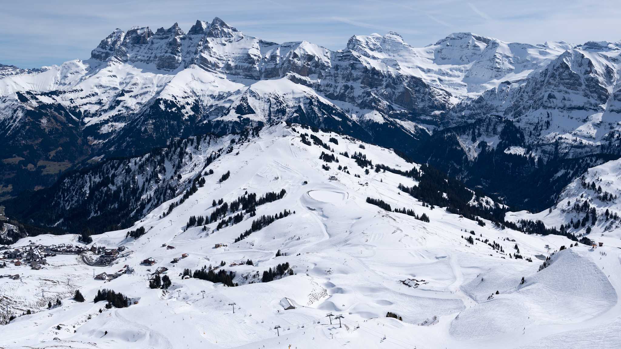 Blick über ein weites schneebedecktes Tal mit Skiliften.
