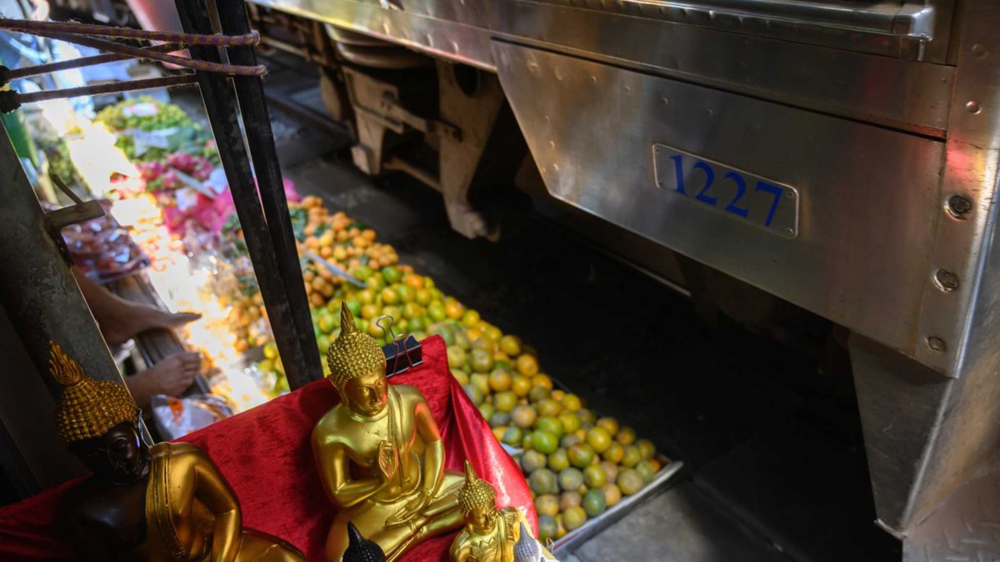 Zwischen Früchten und Buddha-Statuen führt eine Bahnstrecke mitten durch den Mae Klong Markt. © John  Wreford/iStock