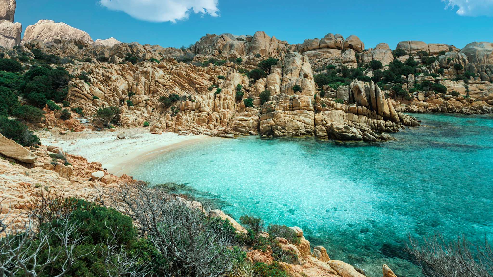 Blick auf eine versteckte Bucht mit kristallklarem Wasser, umrandet von Bergen. © wagnerm25 via Getty Images