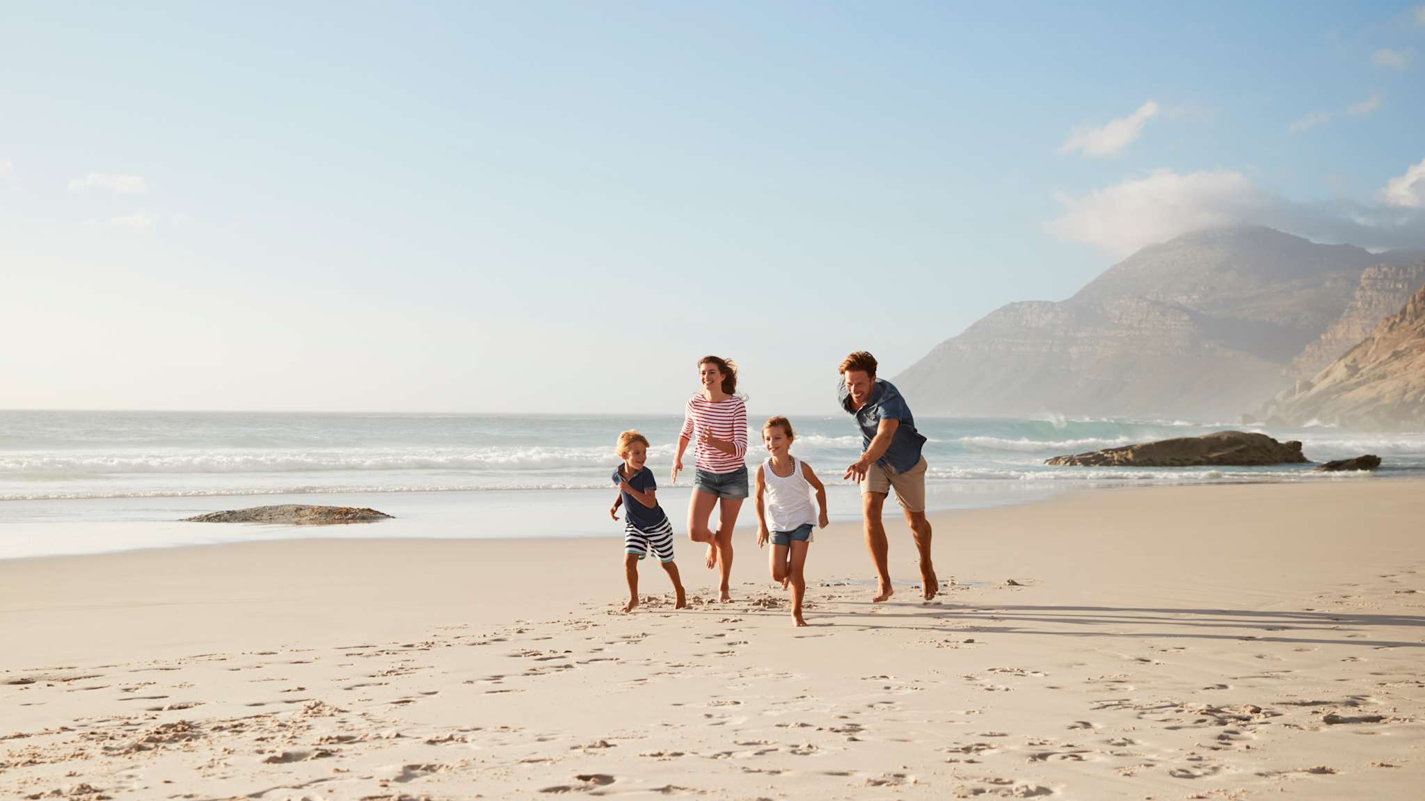 Eine Familie rennt am Strand entlang.