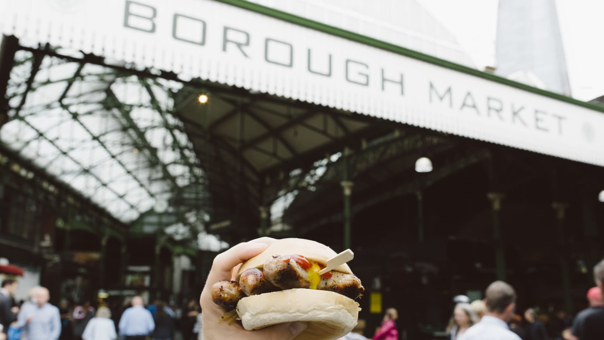 Ein Mann hält ein Sandwich vor dem Borough Market in London.