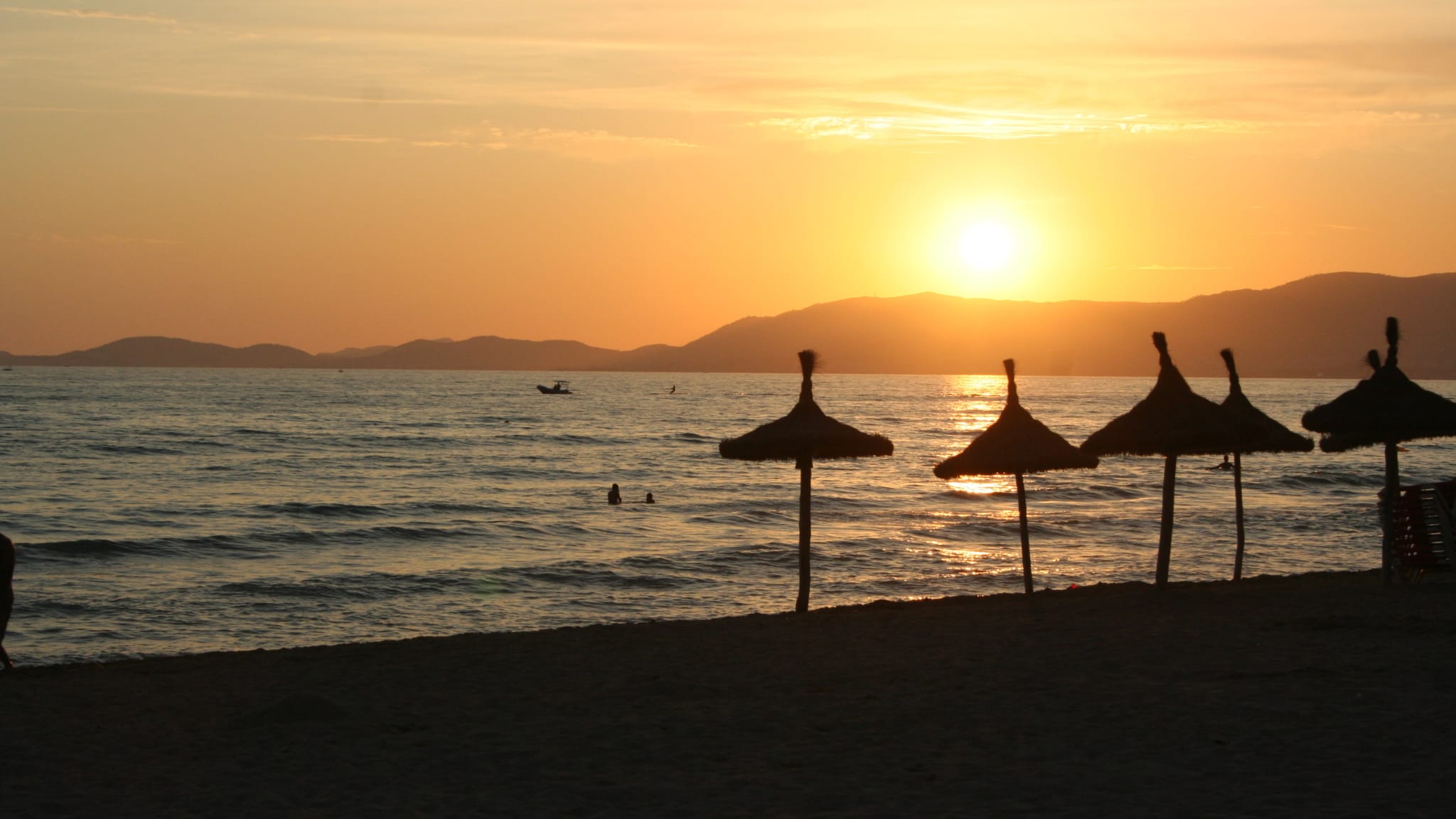 Playa de Palma auf Mallorca mit Strohschirmen bei Sonnenuntergang
