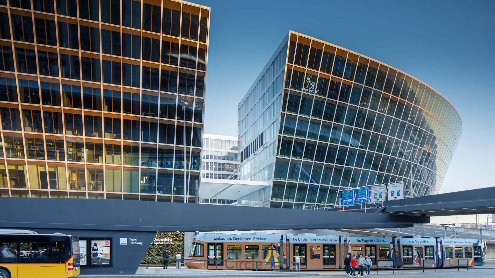 Eine Tramstation vor einem Glasgebäude