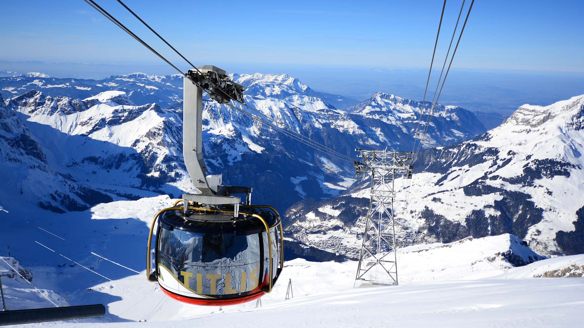 Eine moderne Gondel schwebt über einer verschneiten Berglandschaft.