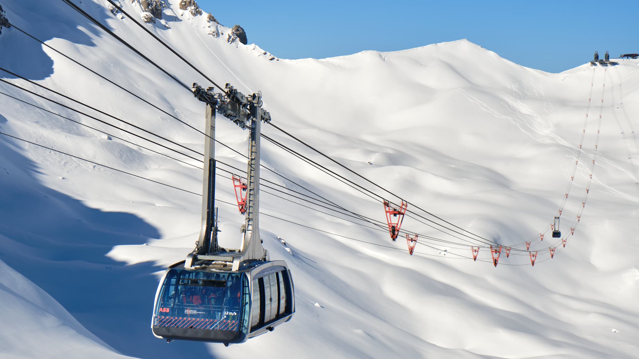 Eine Gondel schwebt über einem verschneiten Berghang.